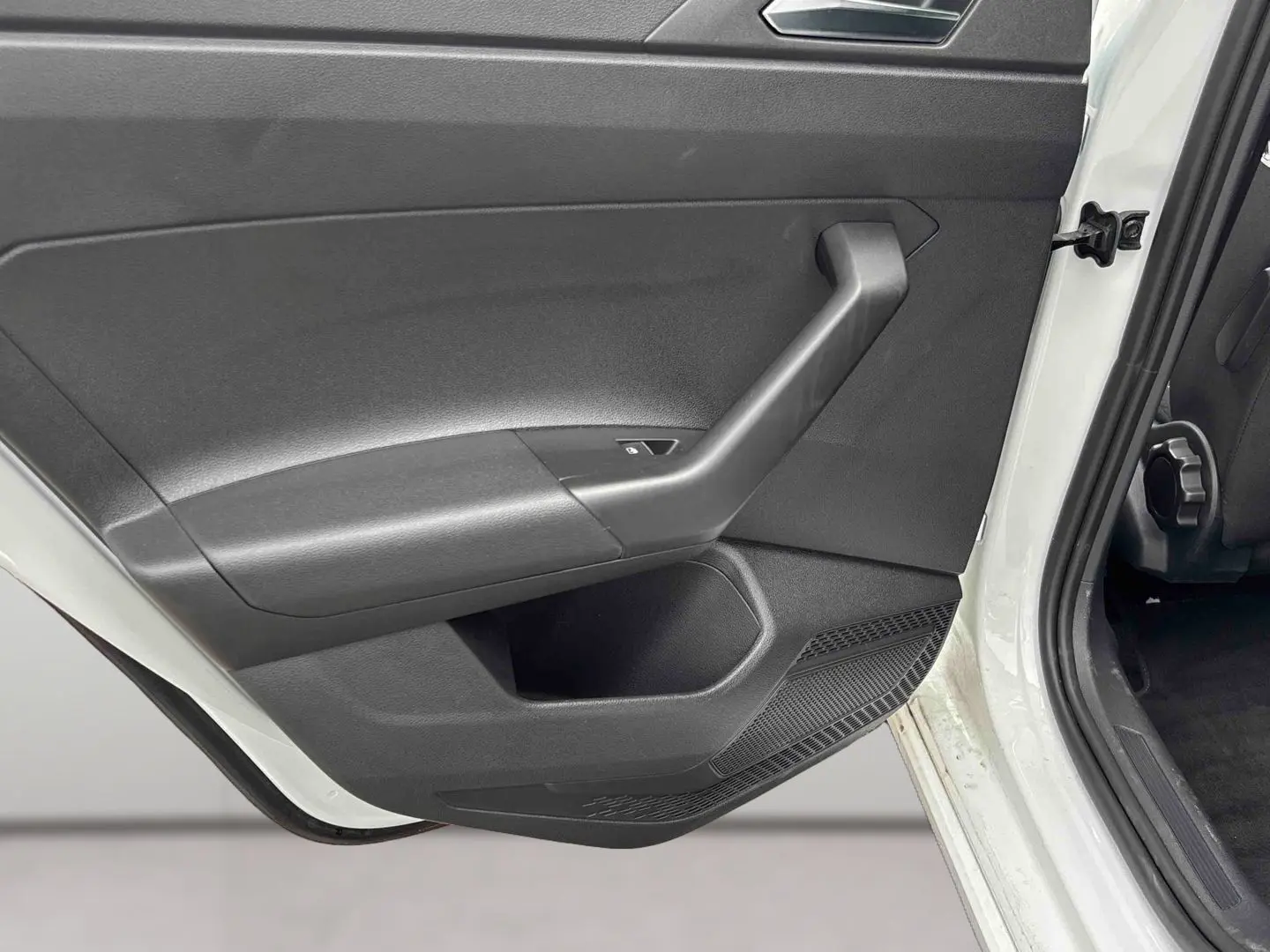 Vue rapprochée de la porte arrière gauche noire ouverte d’un Volkswagen Taigo blanc 2025.