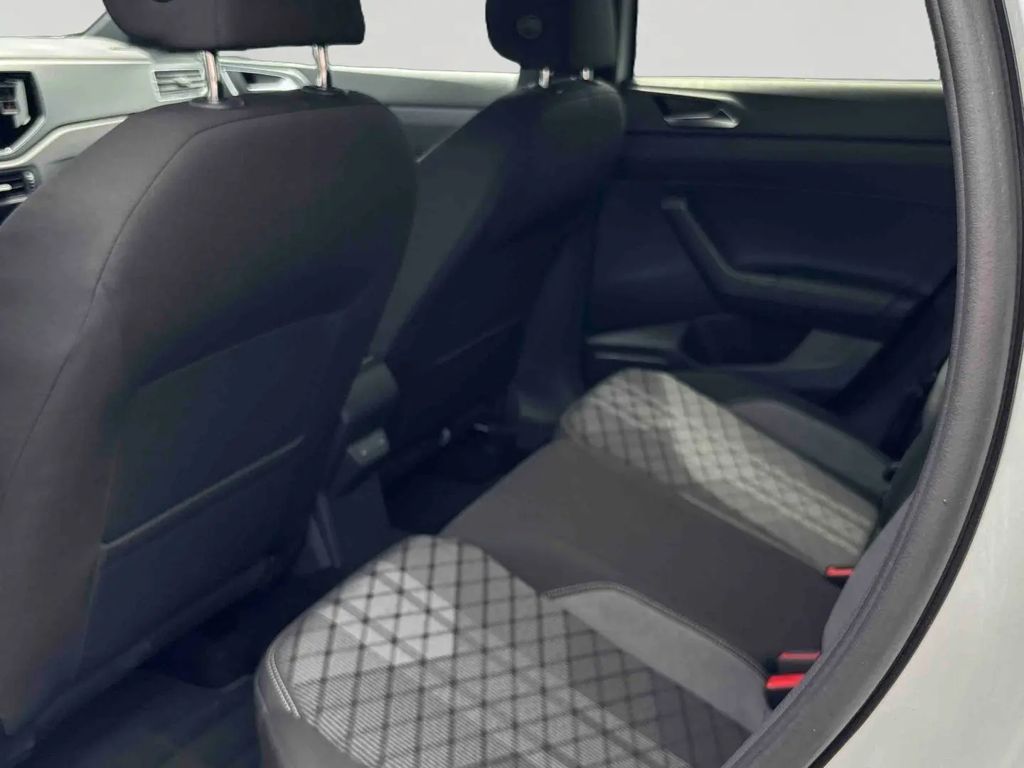 Vue intérieure arrière côté droit du Volkswagen Taigo blanc, sièges arrière avec tissu à motifs géométriques gris et noirs.