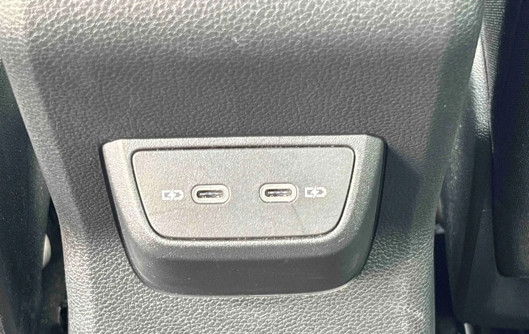 Gros plan sur deux ports USB-C pour charge situés à l'arrière d'un Volkswagen Taigo blanc.