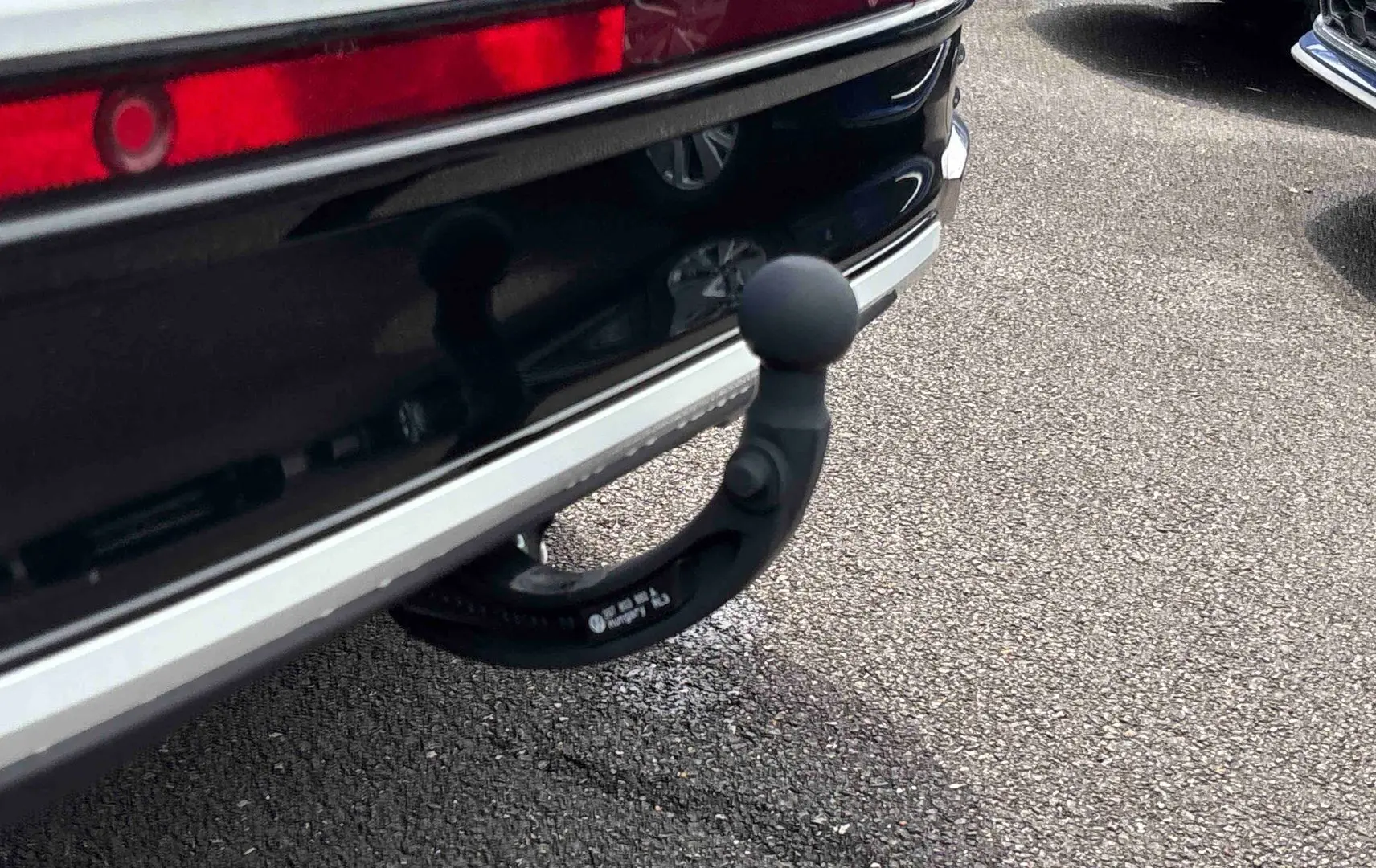 Gros plan sur l'attelage amovible noir sous le pare-chocs arrière blanc du Volkswagen Taigo.
