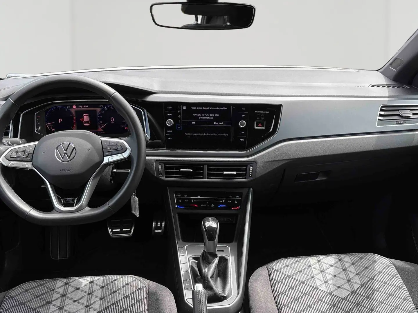 Vue intérieure avant du Volkswagen Taigo blanc 2025, volant multifonction et écran tactile central visible.