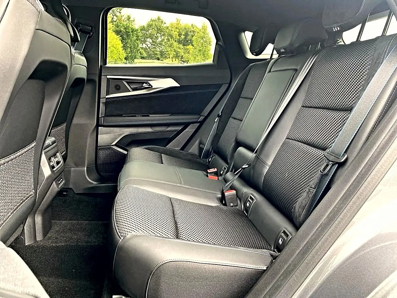Vue latérale droite de la banquette arrière noire en tissu et alcantara du Renault Austral gris schiste, avec accoudoir central relevé.