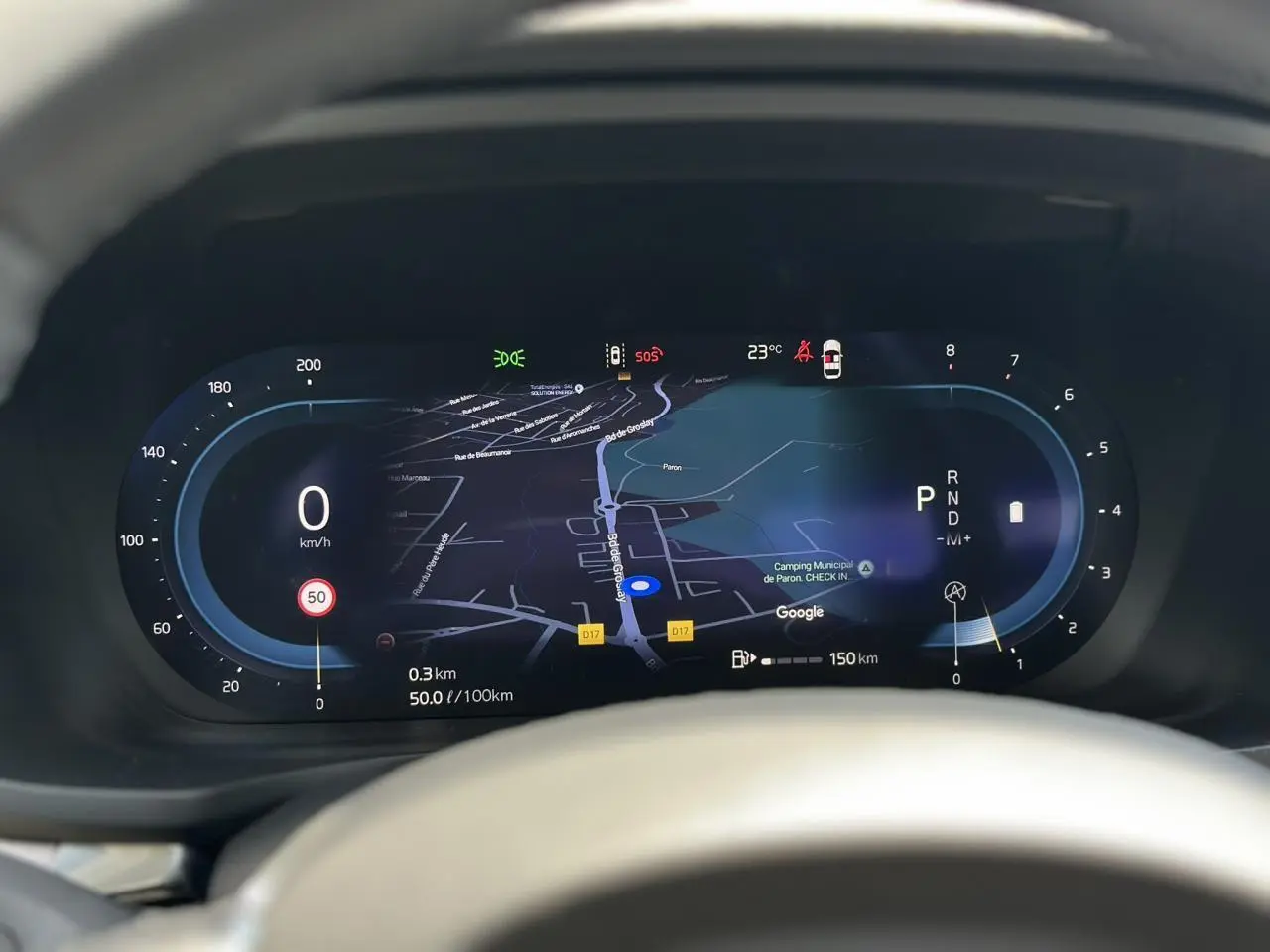 Vue rapprochée du tableau de bord numérique de la Volvo S60 rouge Fusion, affichant la navigation GPS et les indicateurs de vitesse.