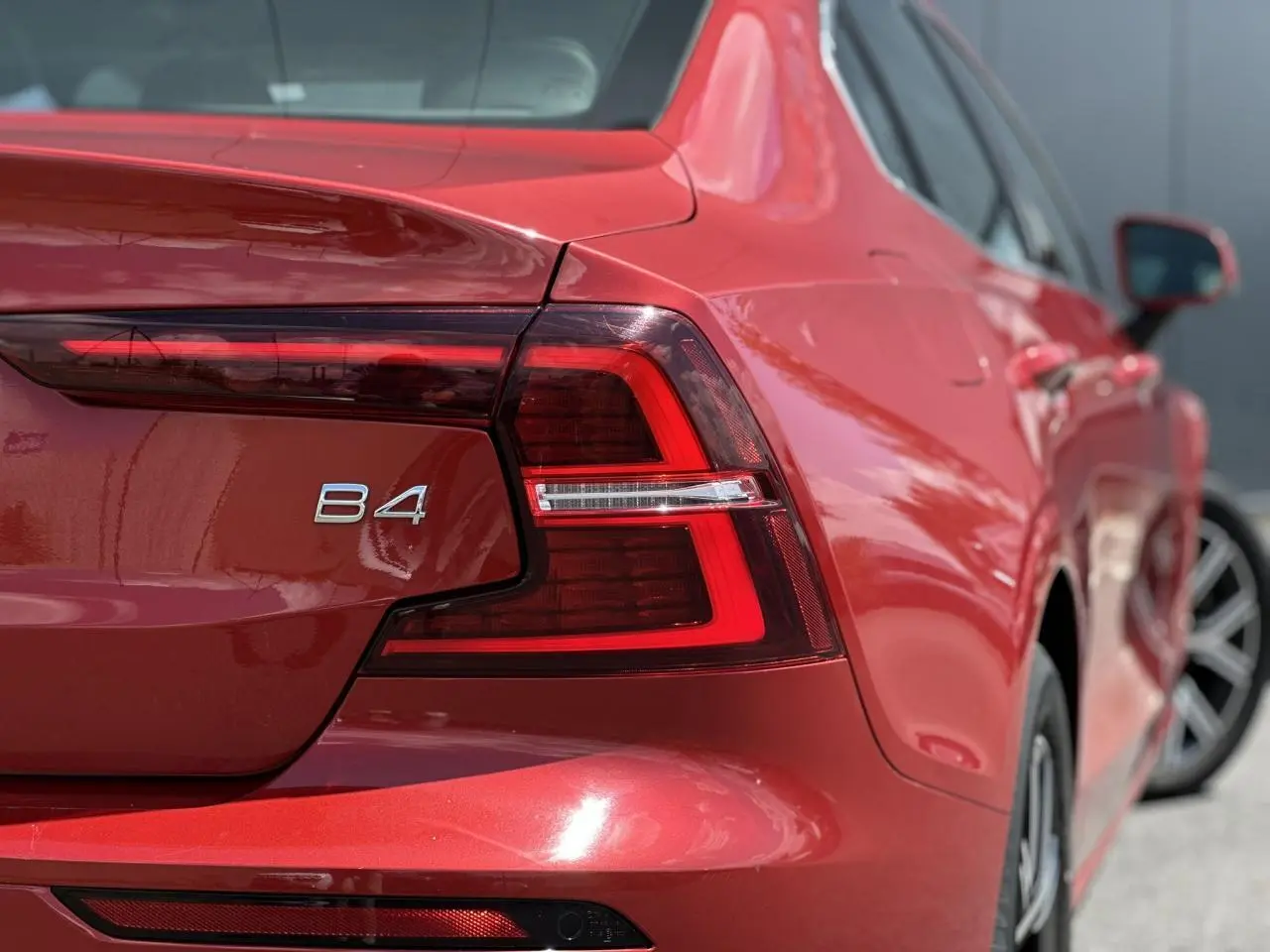 Gros plan sur l'arrière droit rouge Fusion d'une Volvo S60 B4 2024, mettant en valeur le feu LED et l'inscription B4.