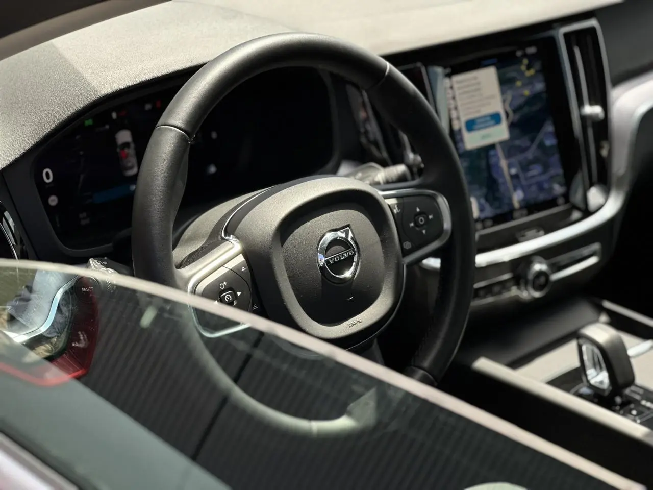 Intérieur de la Volvo S60 rouge Fusion, vue rapprochée du volant et de l'écran tactile central lumineux.