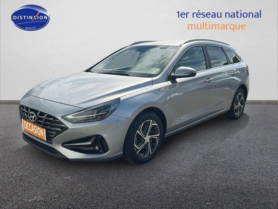 Hyundai i30 SW gris clair vue 3/4 avant droit avec jantes alliage 17 pouces sur fond neutre.