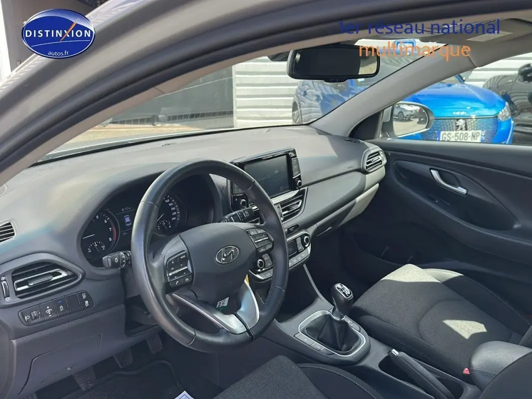 Intérieur de la Hyundai i30 SW 2022 vue côté conducteur, avec tableau de bord moderne et volant multifonction noir.