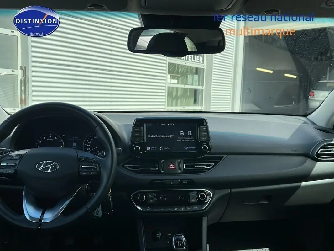 Vue intérieure du tableau de bord et volant noir de la Hyundai i30 SW 2022 avec écran tactile et commandes au volant.