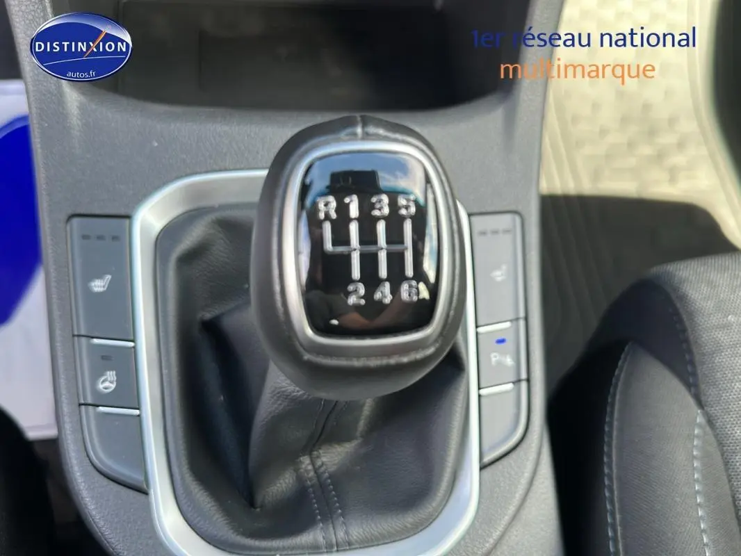 Gros plan sur le levier de vitesses manuel d'une Hyundai i30 SW gris clair, entouré de commandes de sièges chauffants.