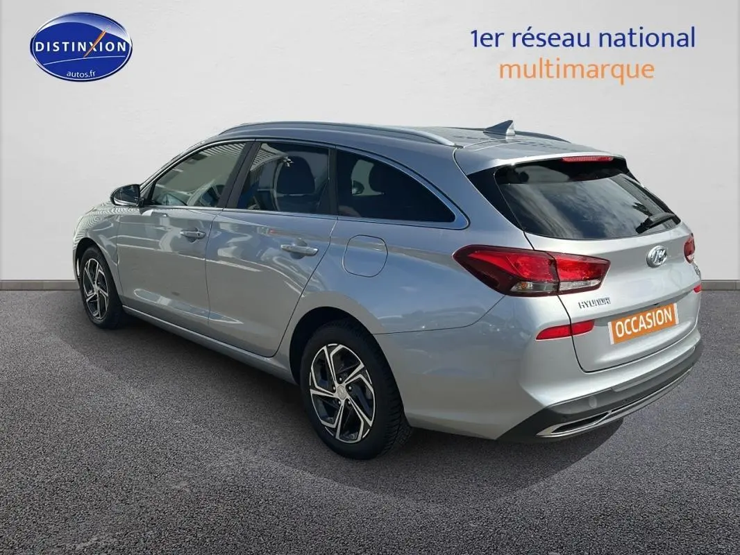 Vue 3/4 arrière droite d'une Hyundai i30 SW gris clair avec jantes alliage 17 pouces et vitres surteintées.