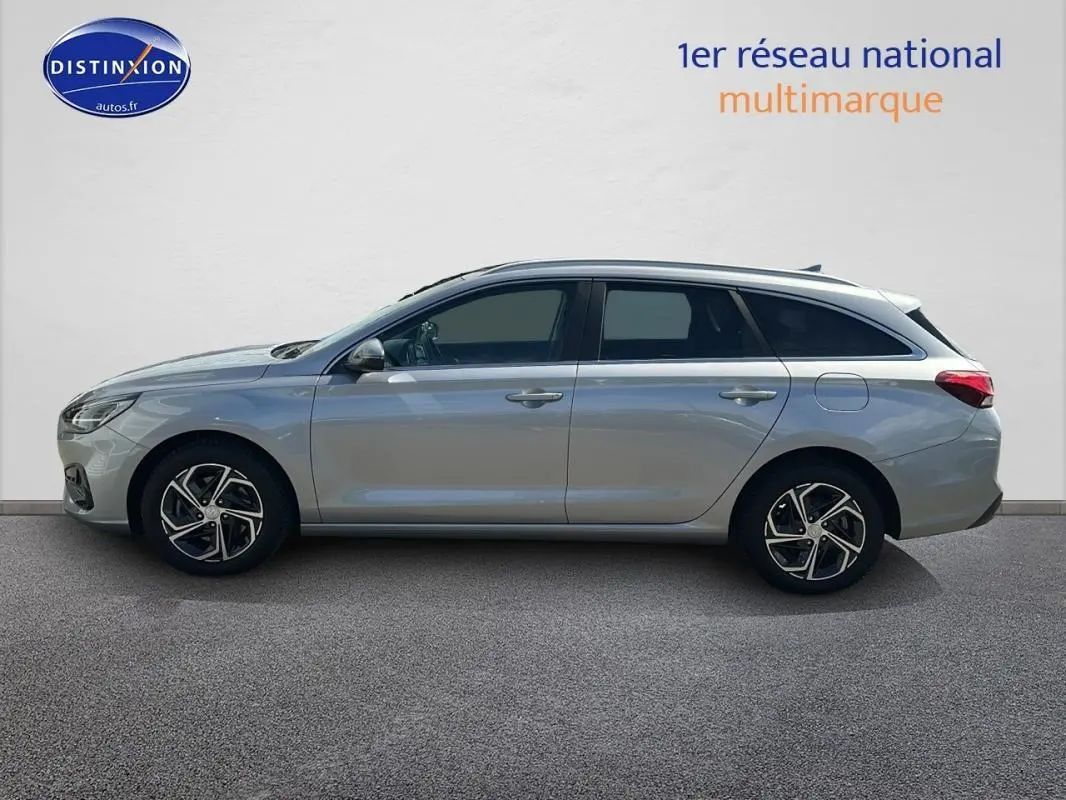 Profil latéral droit d'une Hyundai i30 SW gris clair 2022 avec jantes alliage 17 pouces et vitres surteintées.