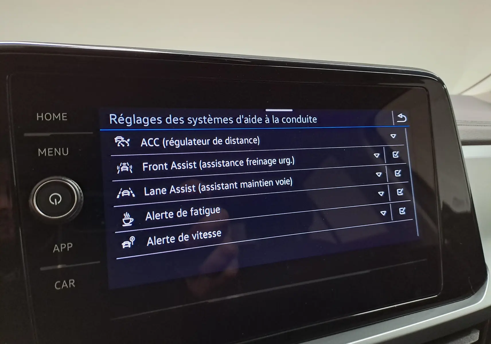 Écran tactile du système d'aide à la conduite du Volkswagen T-Roc 2024 affichant les réglages d'assistances actives.