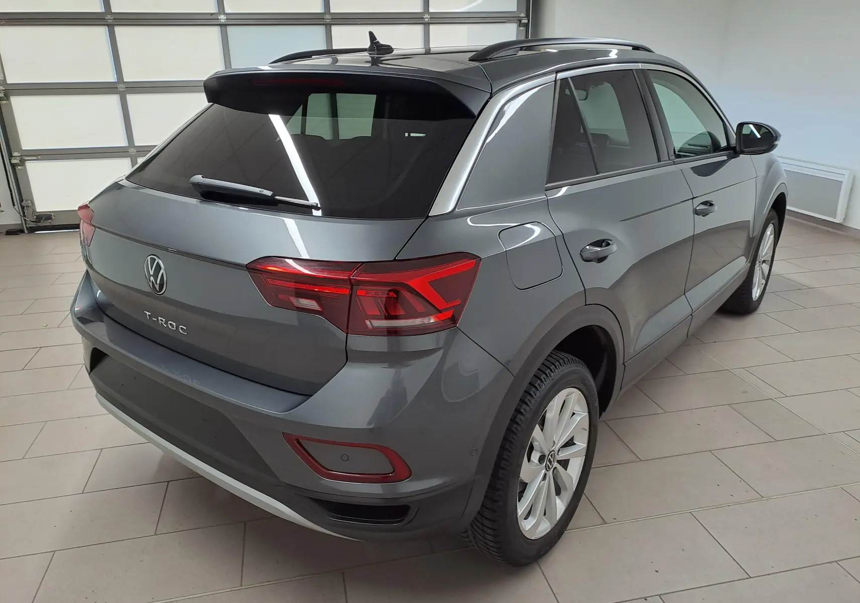 Vue 3/4 arrière droit d'un Volkswagen T-Roc gris Indium avec jantes alliage 17'' Johannesburg en intérieur.