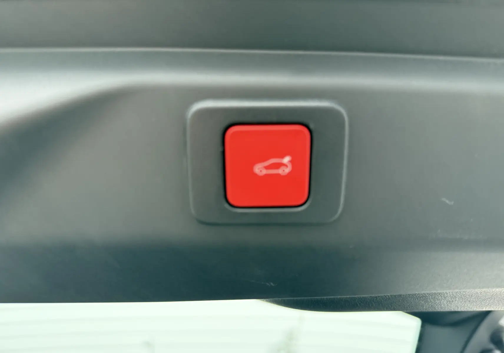 Bouton rouge de fermeture électrique du hayon dans l'habitacle du Peugeot 3008 Hybrid blanc toit noir.