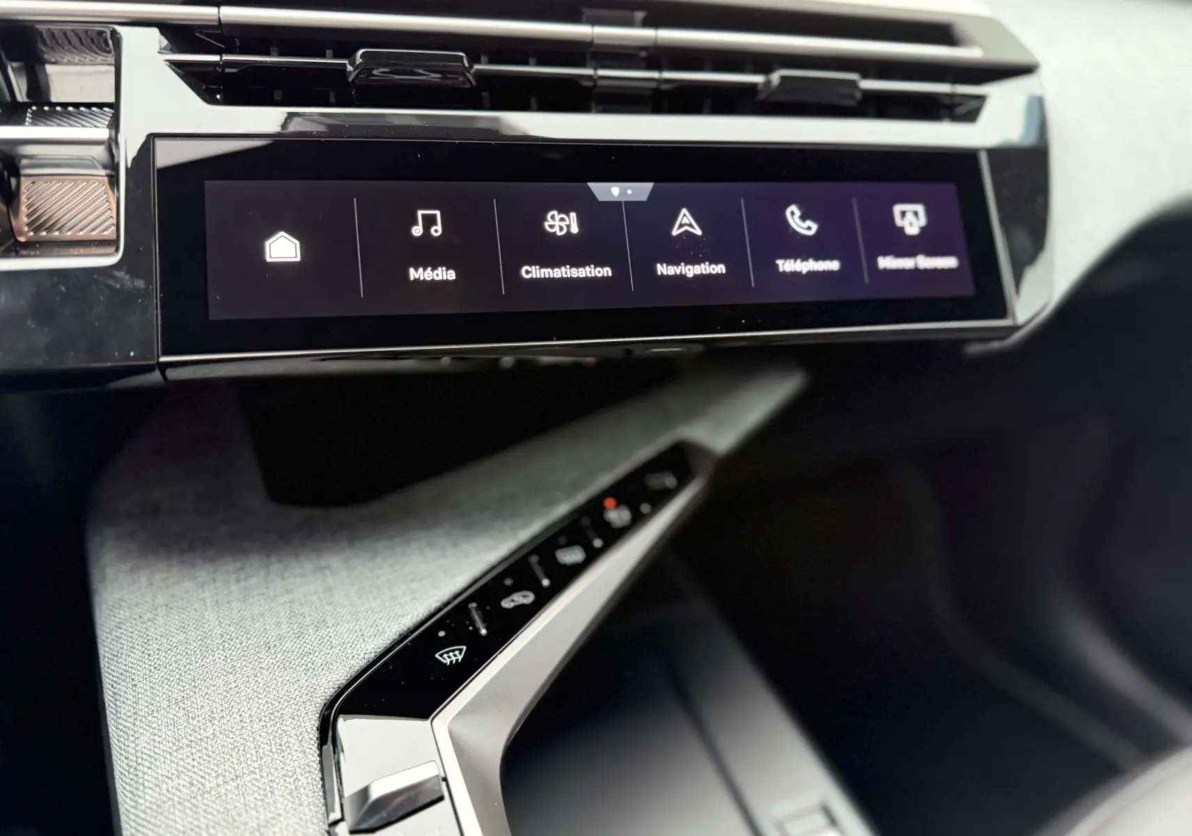 Vue rapprochée de la console centrale et écran tactile du Peugeot 3008 Hybrid 2025 avec finition tissu gris et commandes noires.