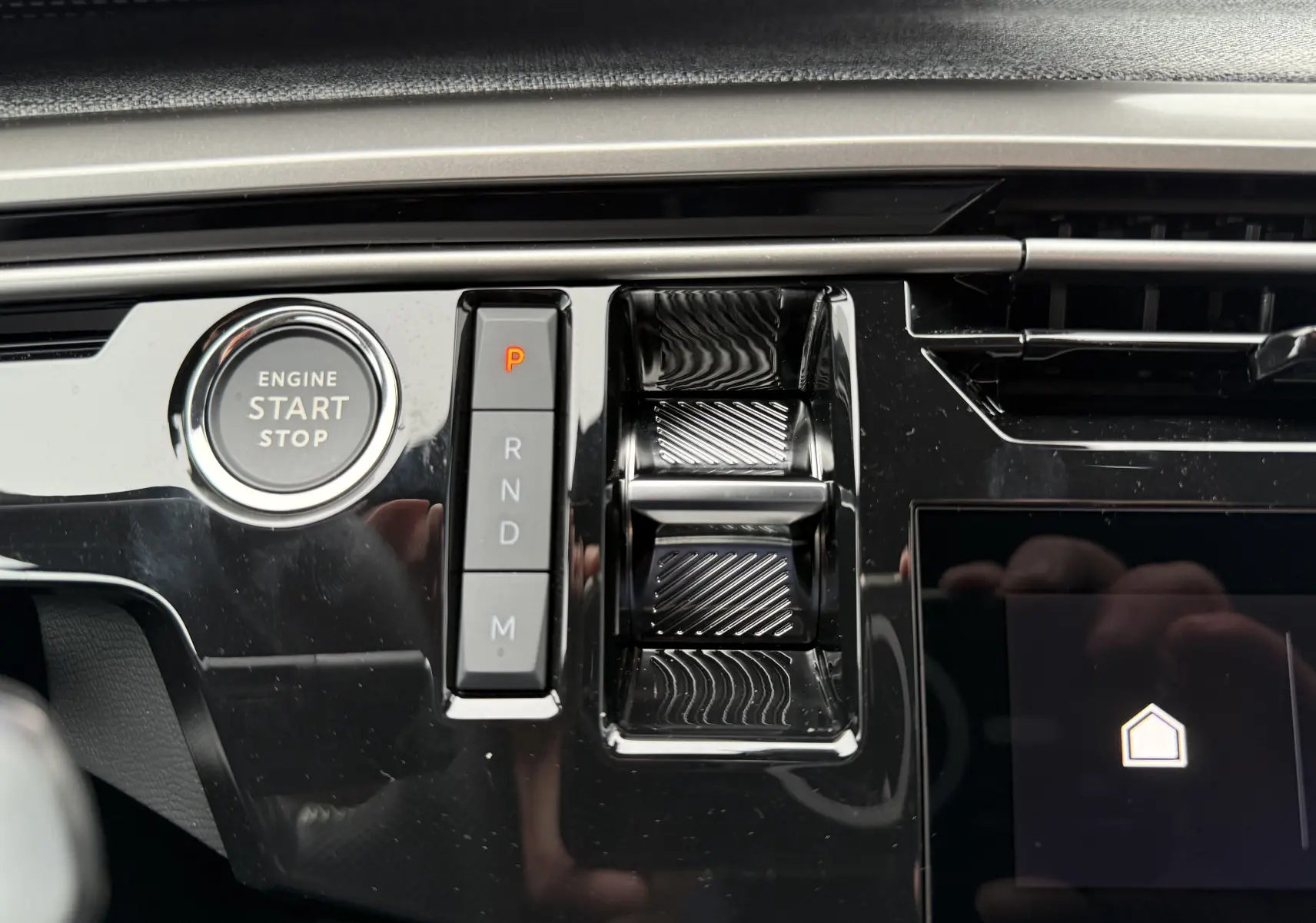 Gros plan sur la console centrale noire brillante du Peugeot 3008 Hybrid avec bouton start/stop et sélecteur de vitesses électronique.