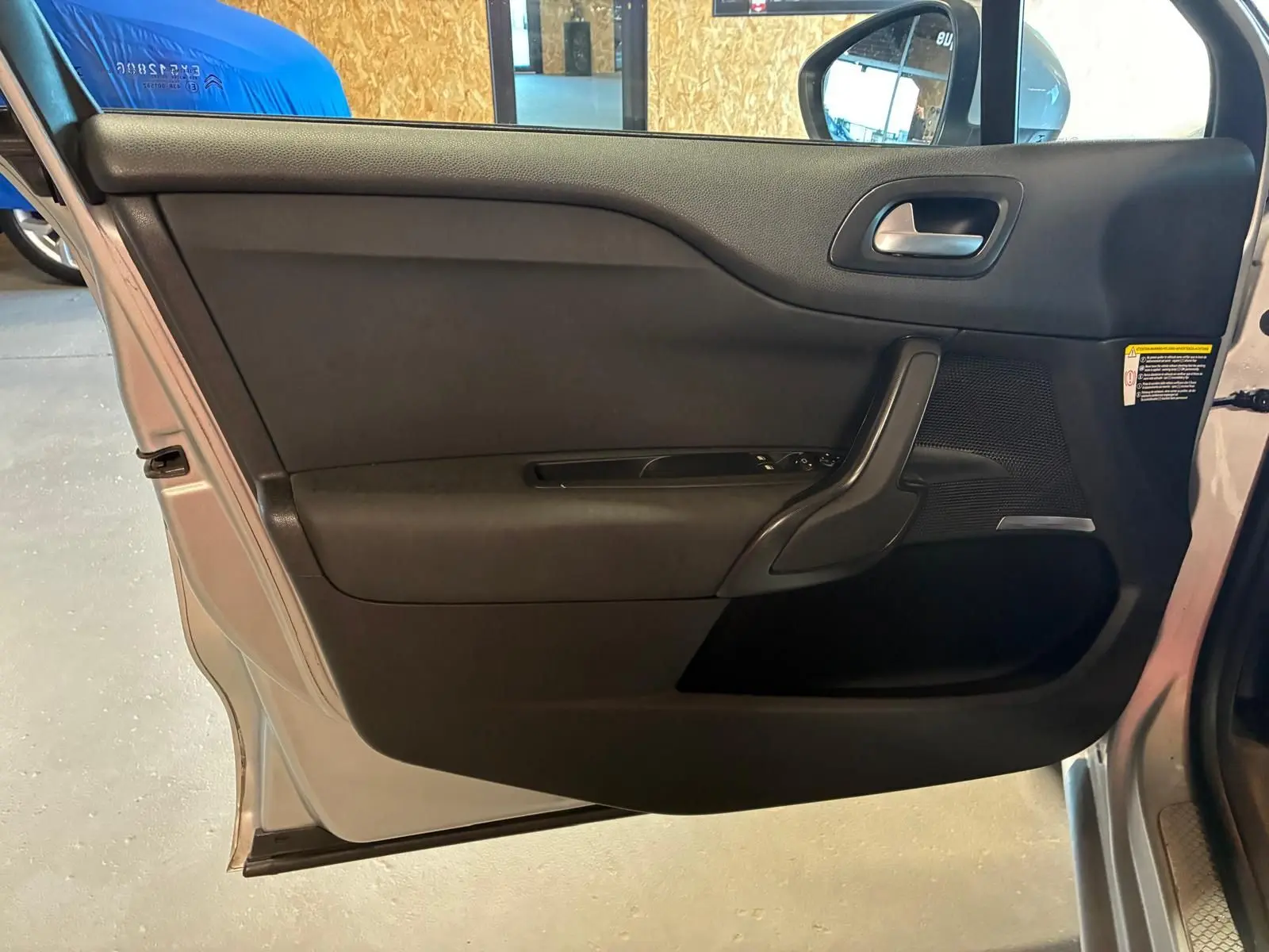 Vue intérieure côté gauche de la porte avant gris clair d’une DS4 2014 avec garniture noire et commandes de vitre.