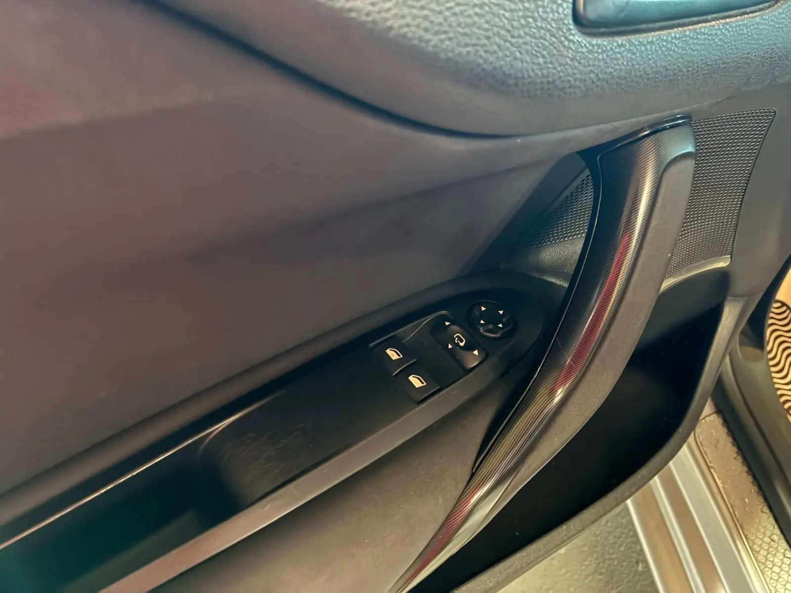 Gros plan sur la poignée intérieure et les commandes de vitres côté conducteur d’une DS4 gris foncé.