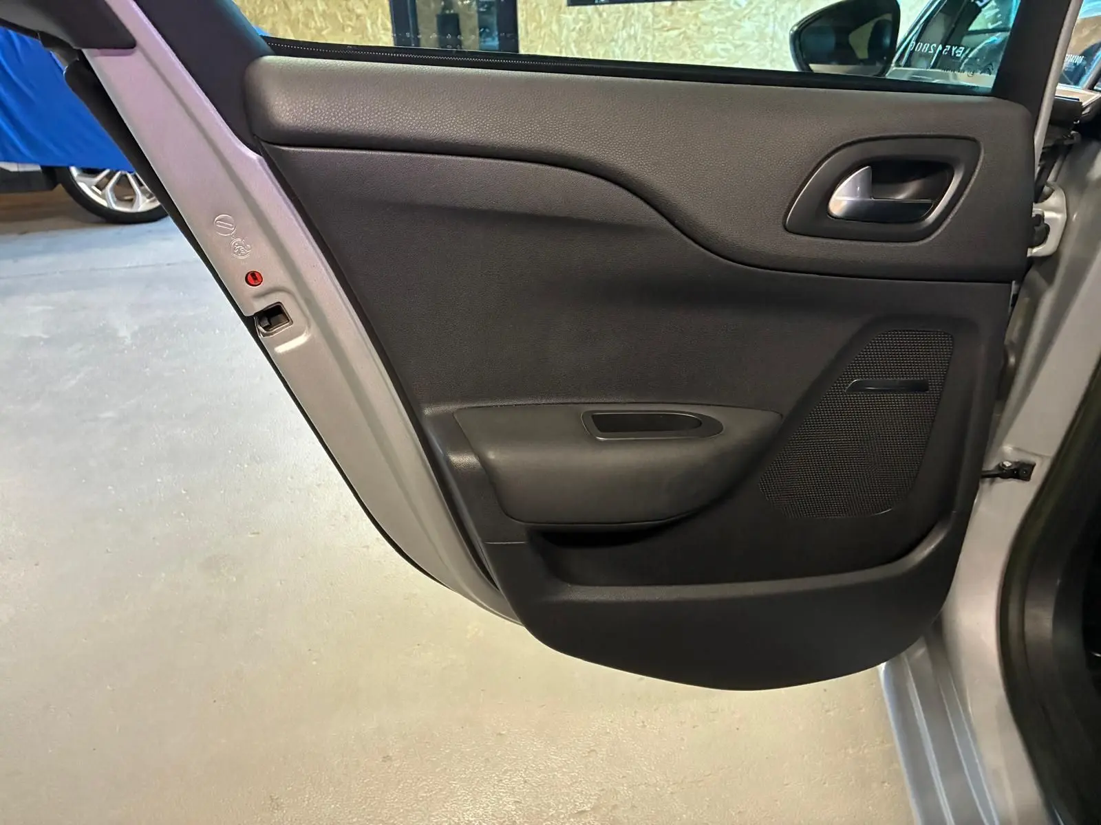 Vue rapprochée de la porte arrière gauche intérieure d'une DS4 gris 2014 avec garniture noire et poignée intégrée.