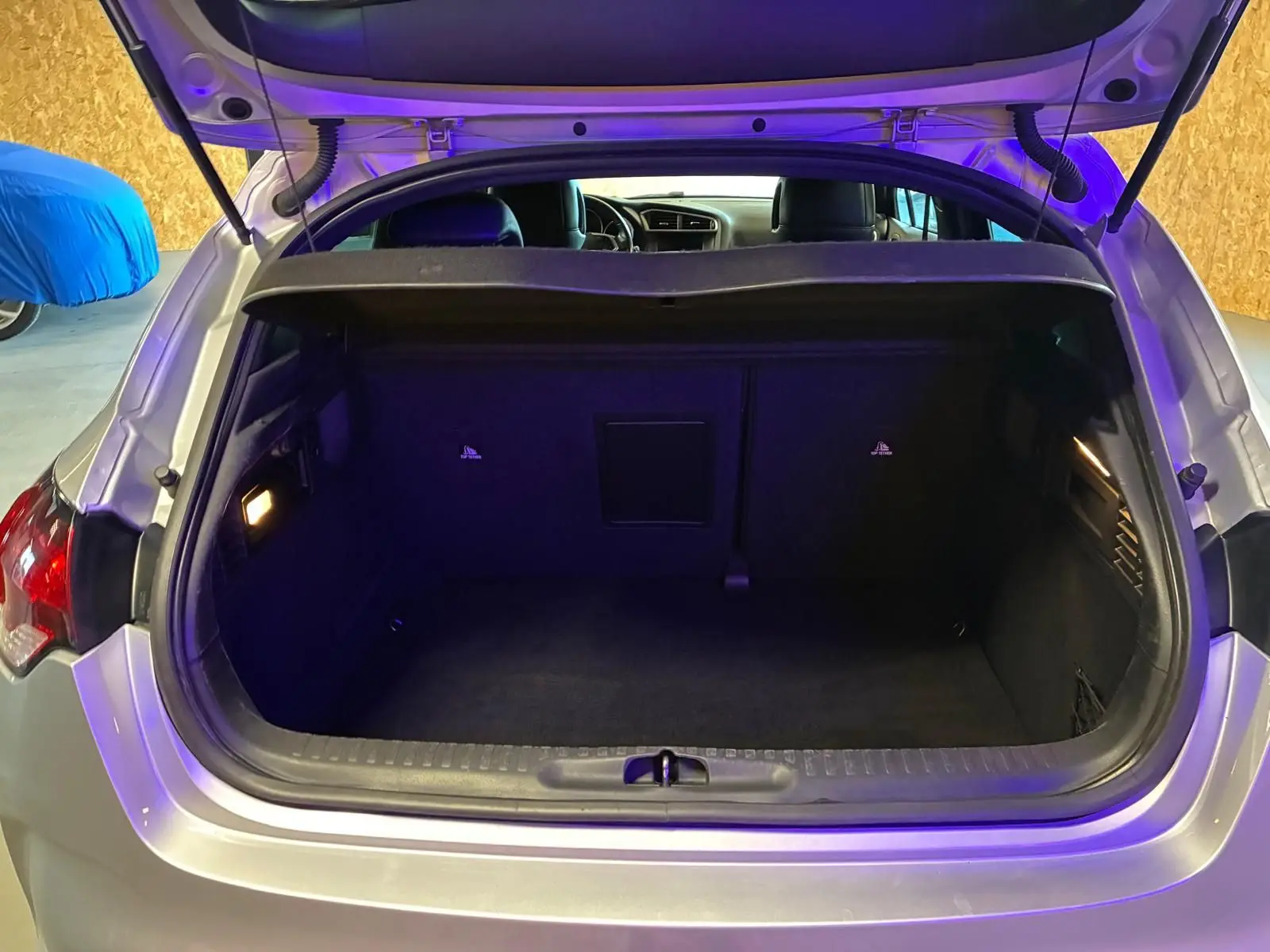 Coffre ouvert d'une DS4 gris clair vue de l'arrière, montrant un espace de chargement propre et éclairé.