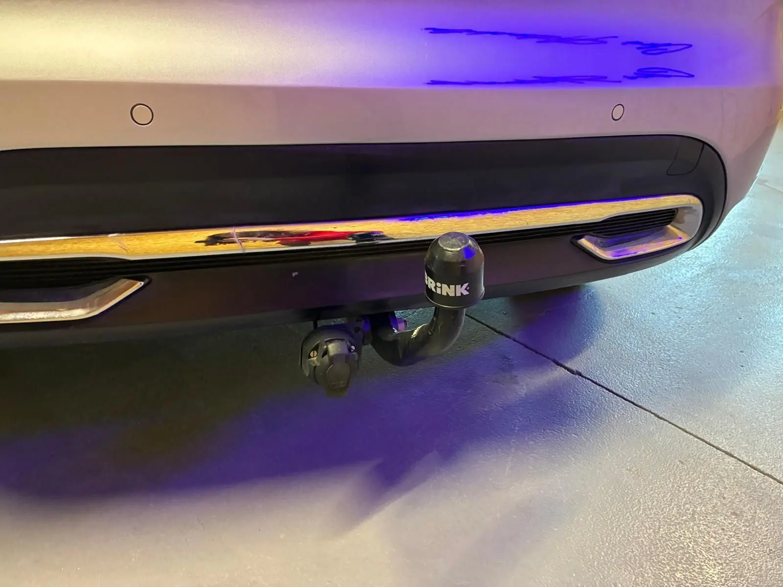 Gros plan sur l'attelage de remorque noir fixé au pare-chocs arrière gris d'une DS4 2014.