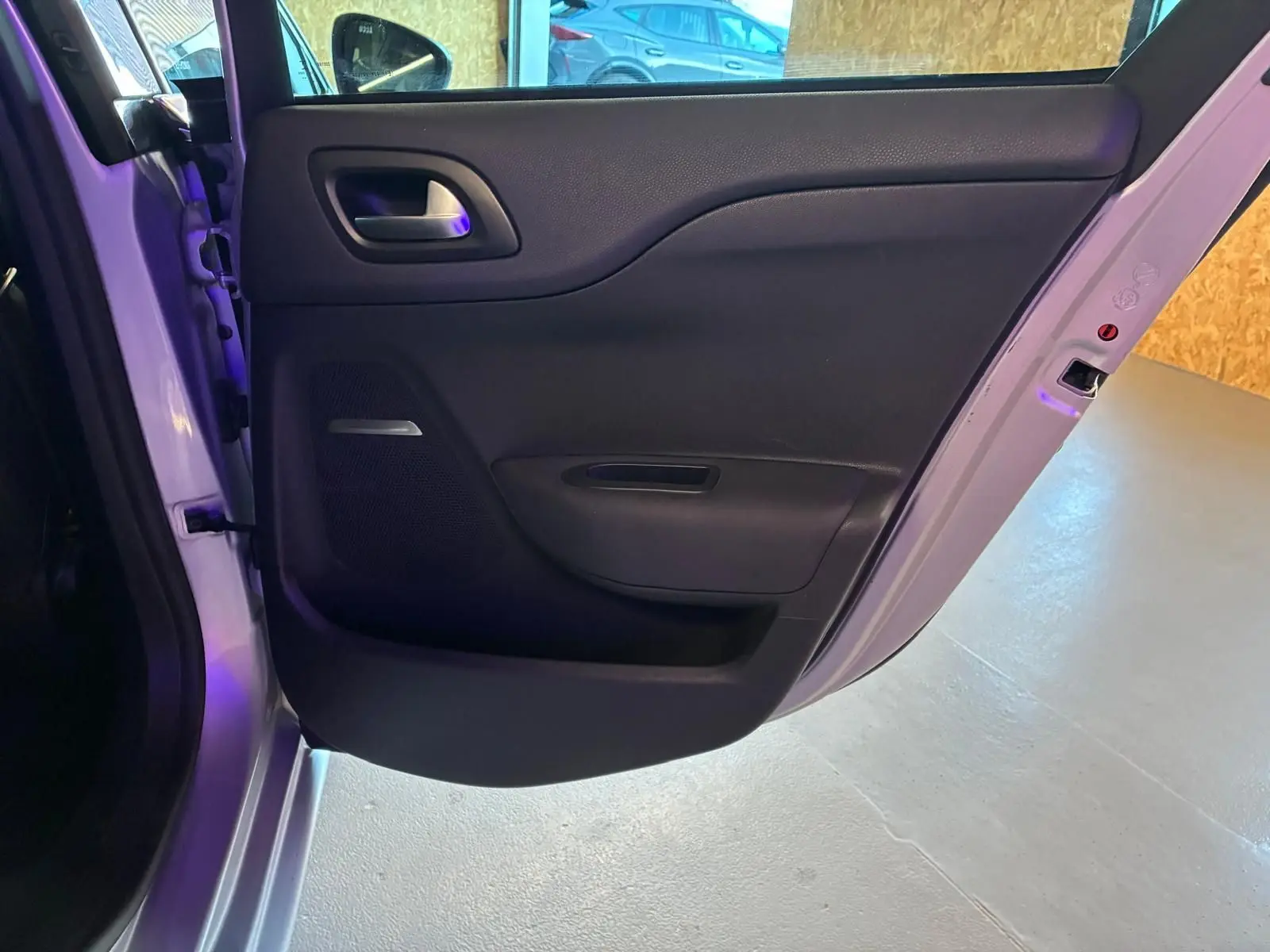 Vue intérieure de la porte arrière gauche ouverte d'une DS4 gris 2014, avec habillage noir et poignée argentée.