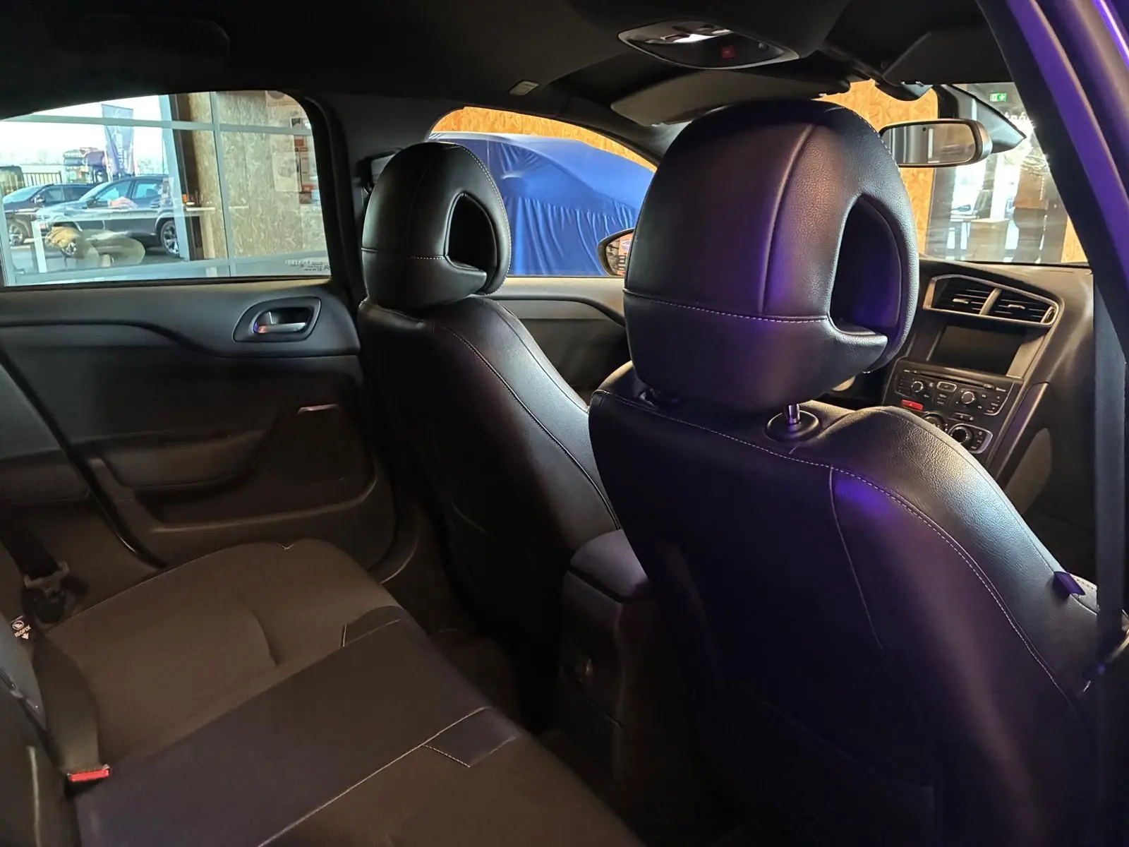 Vue intérieure arrière droite de la DS4 gris, montrant les sièges avant en cuir noir et la console centrale.