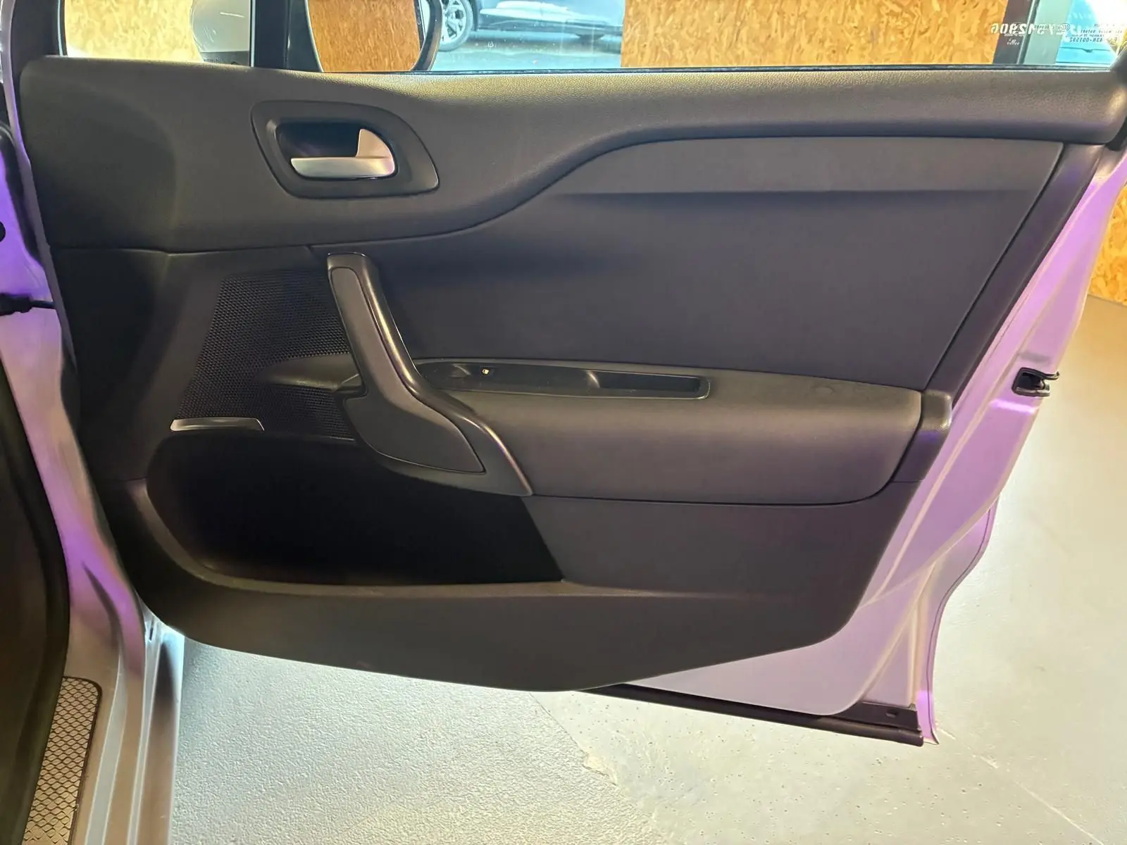 Vue intérieure de la porte côté gauche d'une DS4 gris 2014, avec poignée noire et garniture tissu gris-noir.