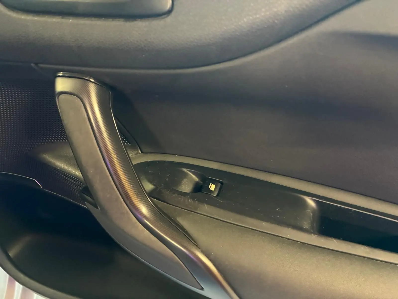 Poignée de porte intérieure côté gauche de la DS4 gris foncé, avec bouton de verrouillage intégré.