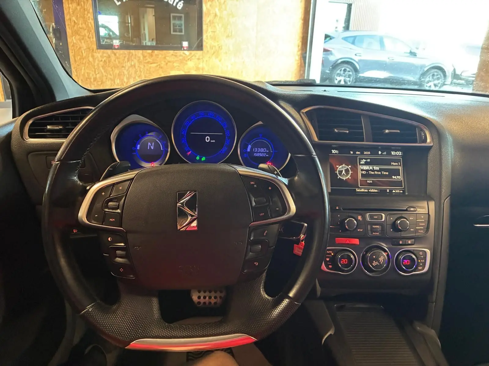 Vue intérieure centrée sur le volant et le tableau de bord du DS4 gris, avec affichage digital et commandes au volant.