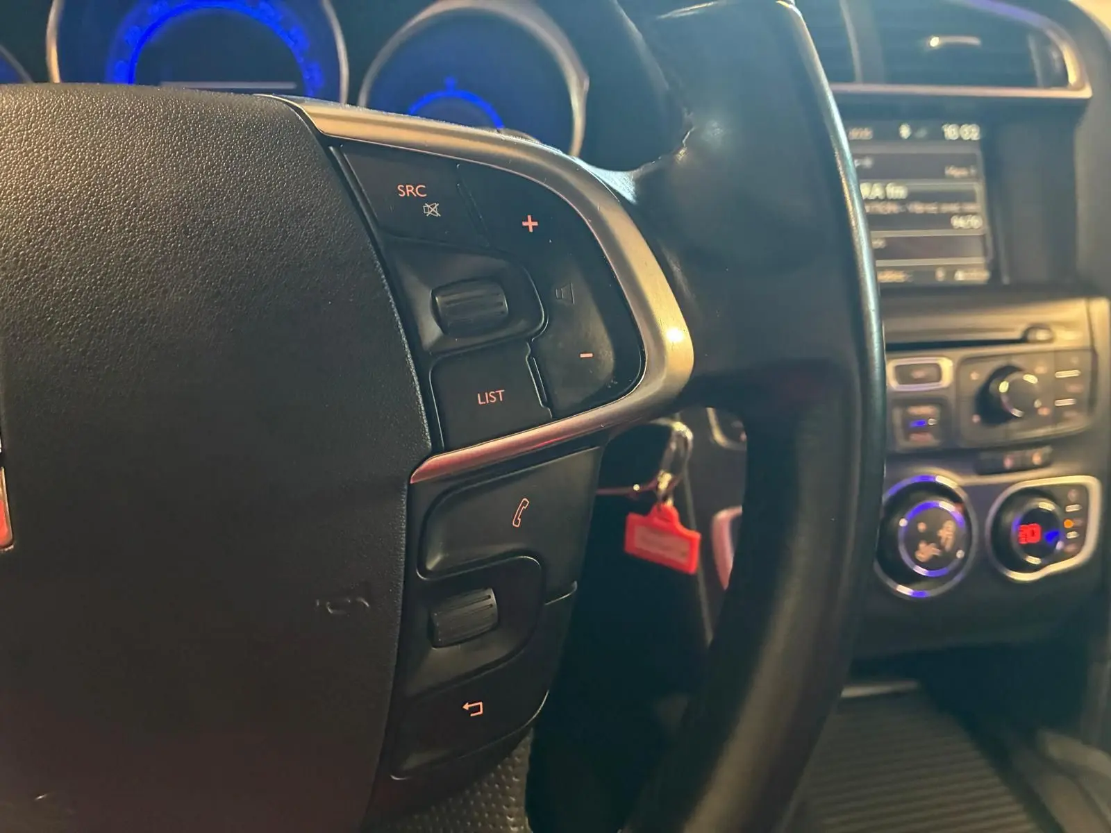 Gros plan sur le volant noir de la DS4 2014 avec commandes intégrées, tableau de bord et console centrale en arrière-plan.