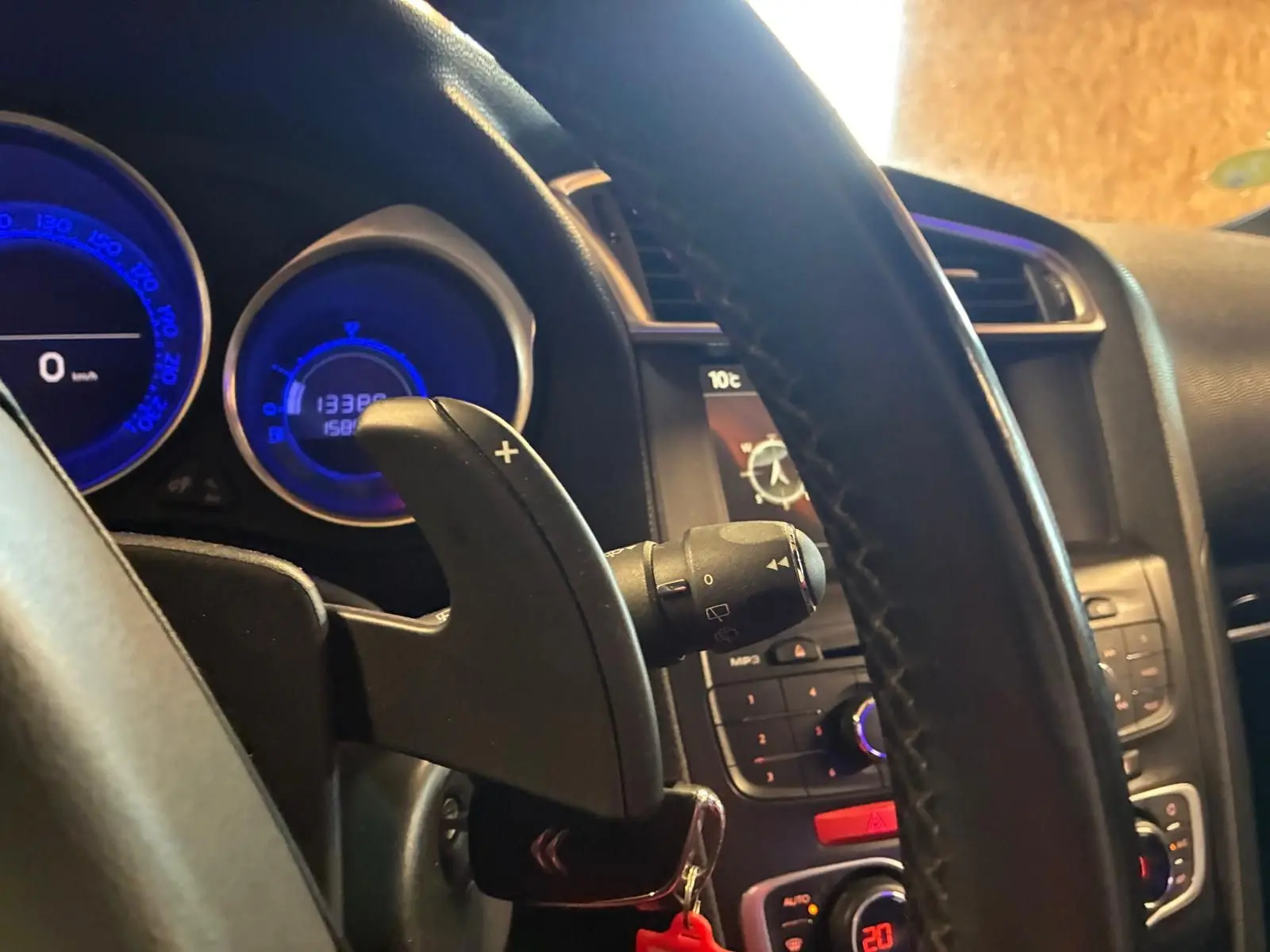 Gros plan sur le volant et le tableau de bord du DS4 gris, avec affichage digital bleu et commande de boîte auto visible.