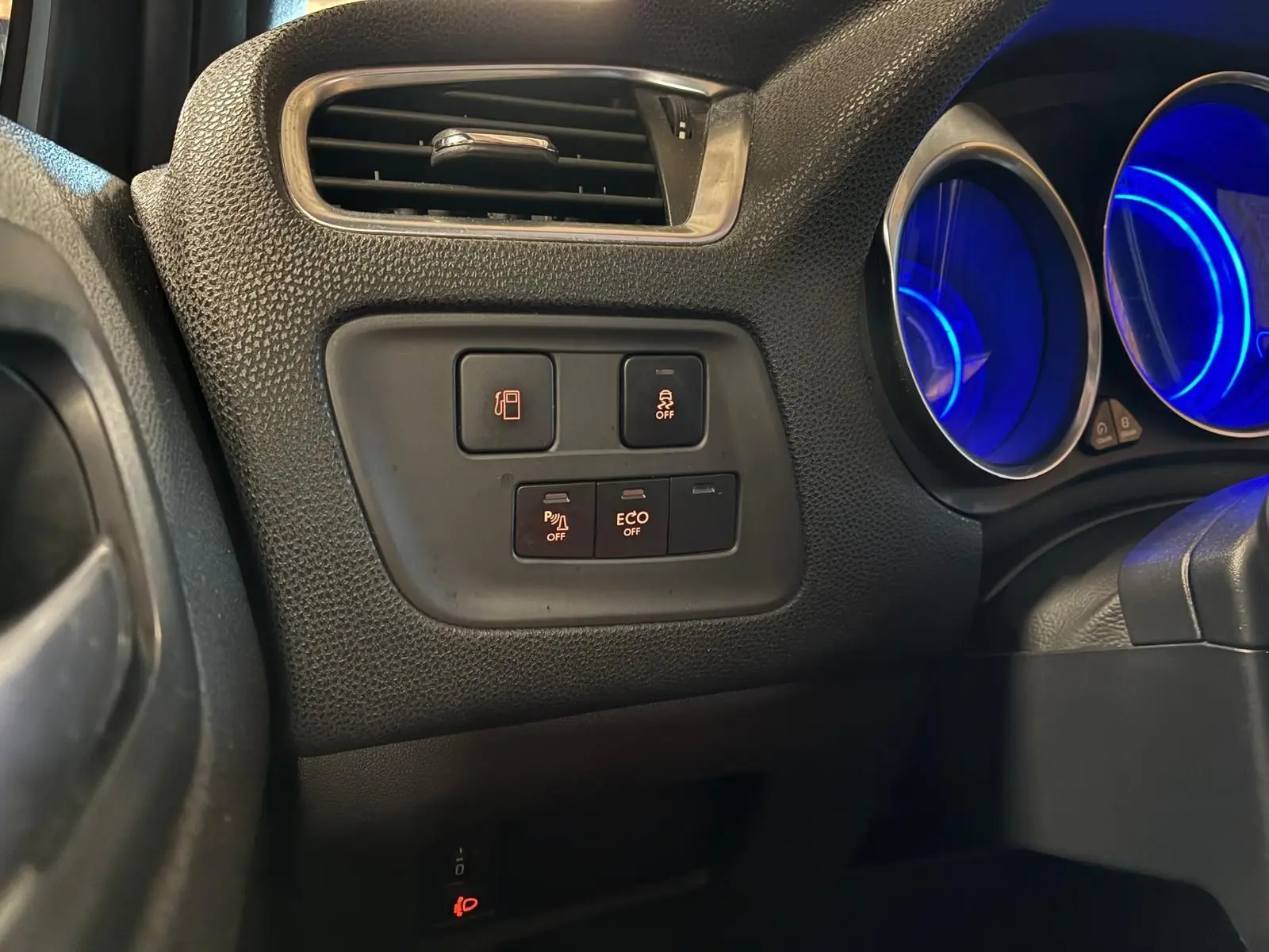 Détail intérieur côté gauche du tableau de bord gris noir du DS4 2014, avec commandes d’aide à la conduite et compteurs bleus éclairés.