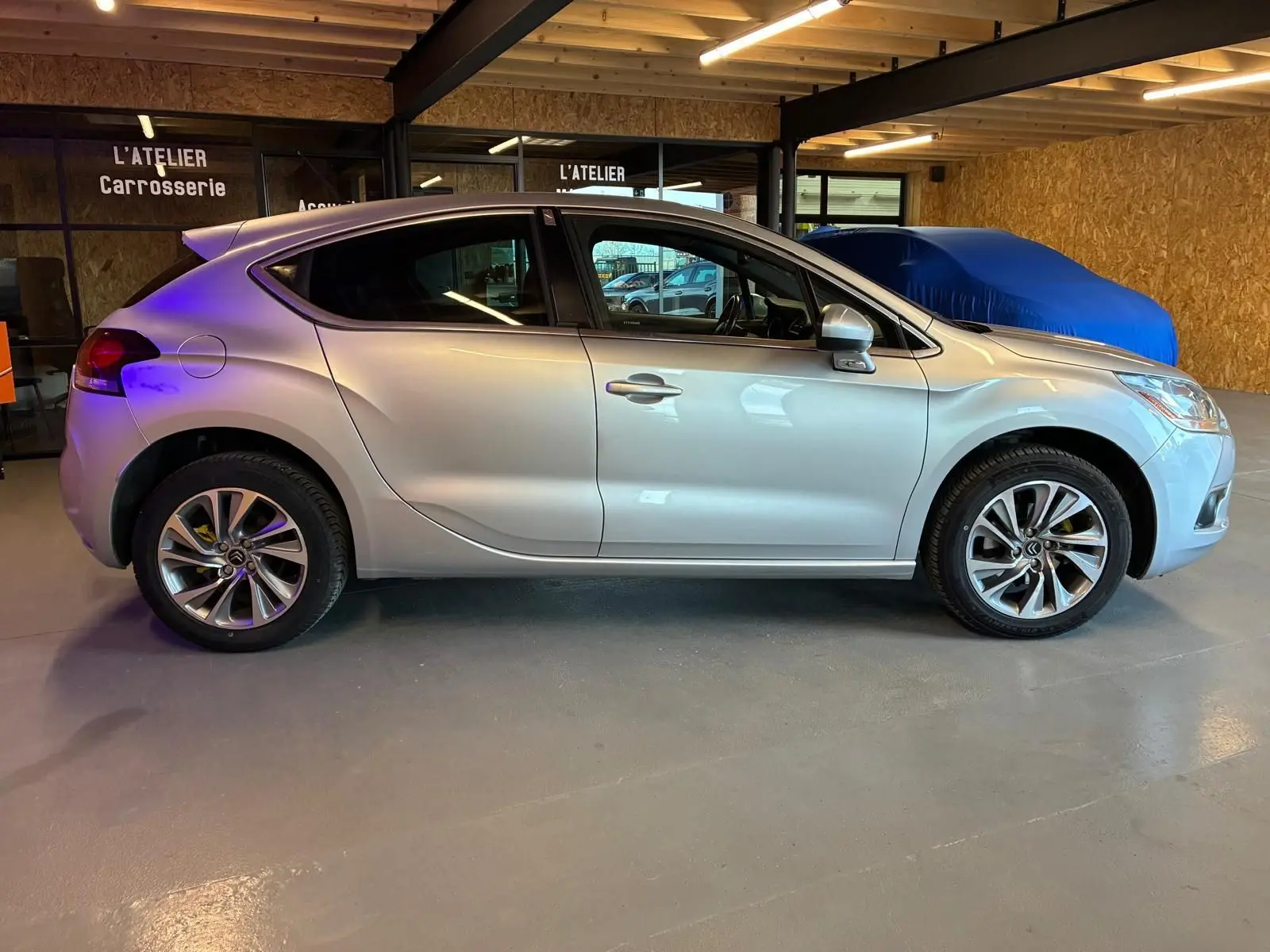 Vue latérale droite d'une DS4 gris clair 2014 stationnée en intérieur, mettant en valeur ses lignes fluides et ses jantes alliage.