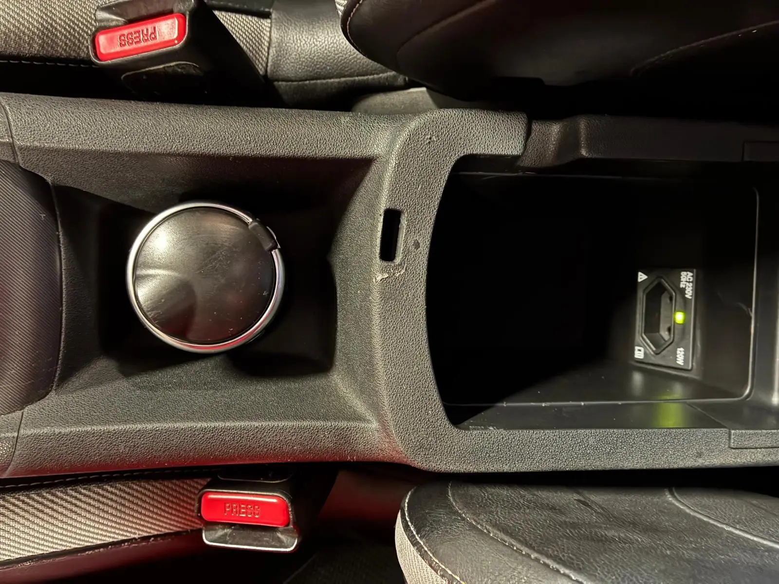 Vue rapprochée de la console centrale de la DS4 gris, montrant un porte-gobelet, un rangement et les ceintures de sécurité rouges.