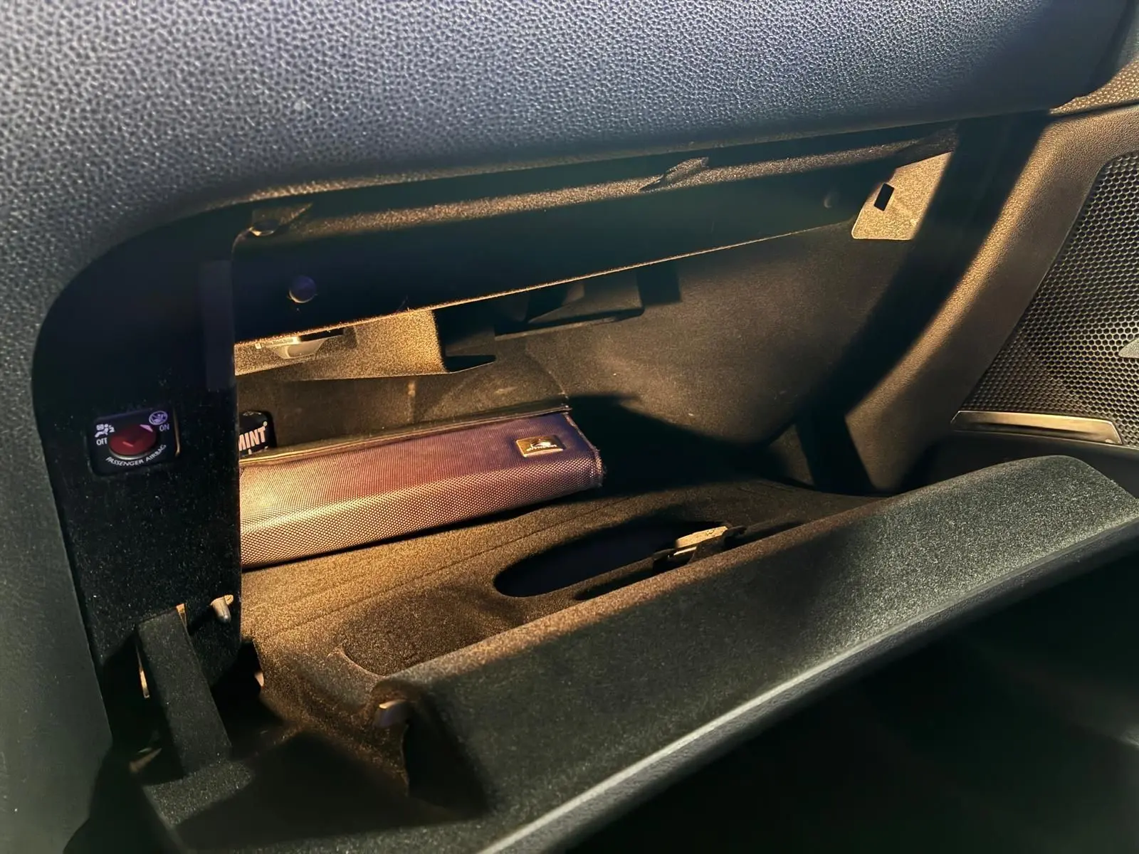 Gros plan sur la boîte à gants ouverte côté passager du DS4 gris, montrant un étui bleu à l'intérieur.