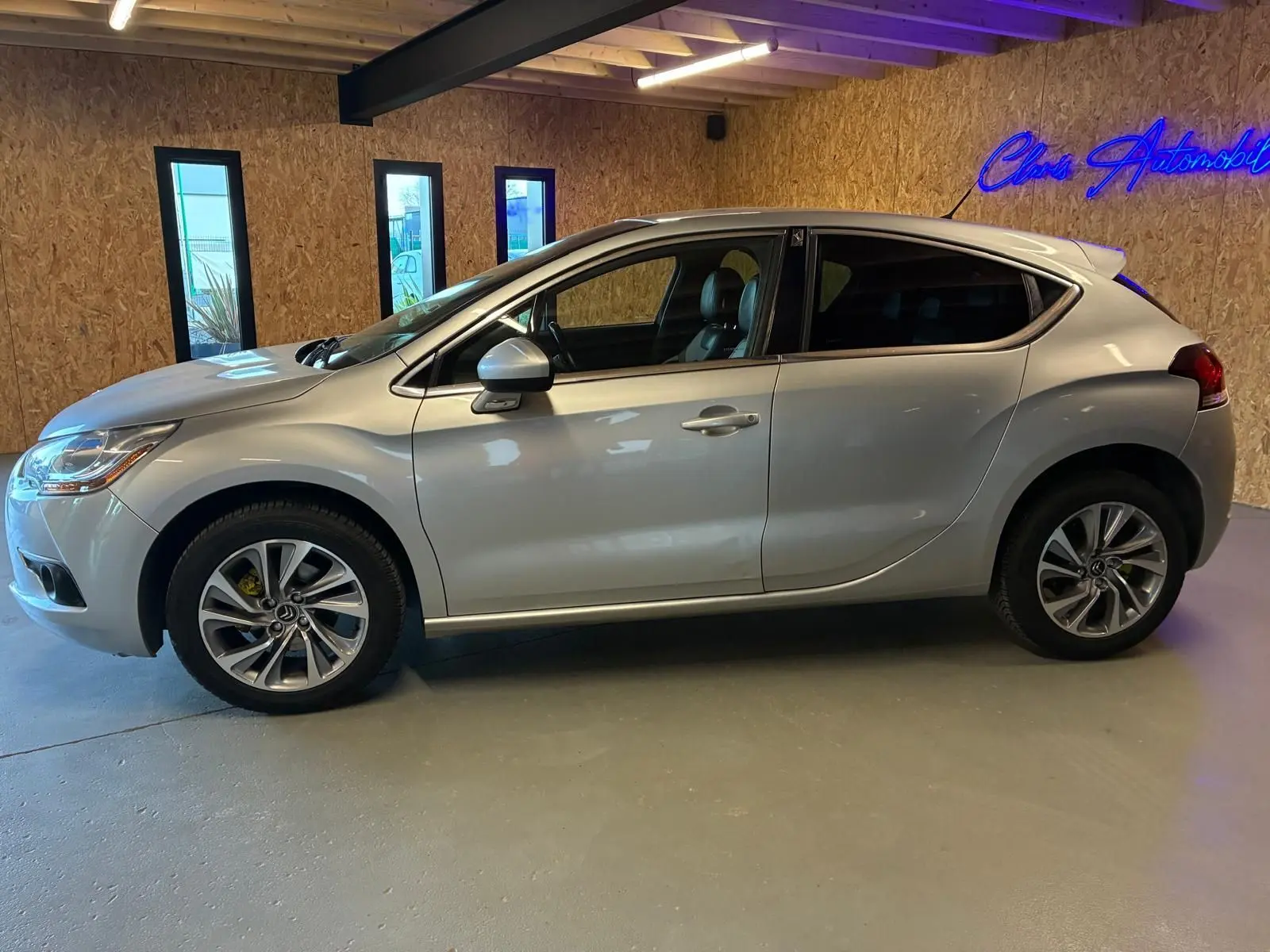 Vue de profil côté gauche d'une DS4 gris métallisé 2014, avec jantes alliage et vitres teintées, en intérieur showroom.