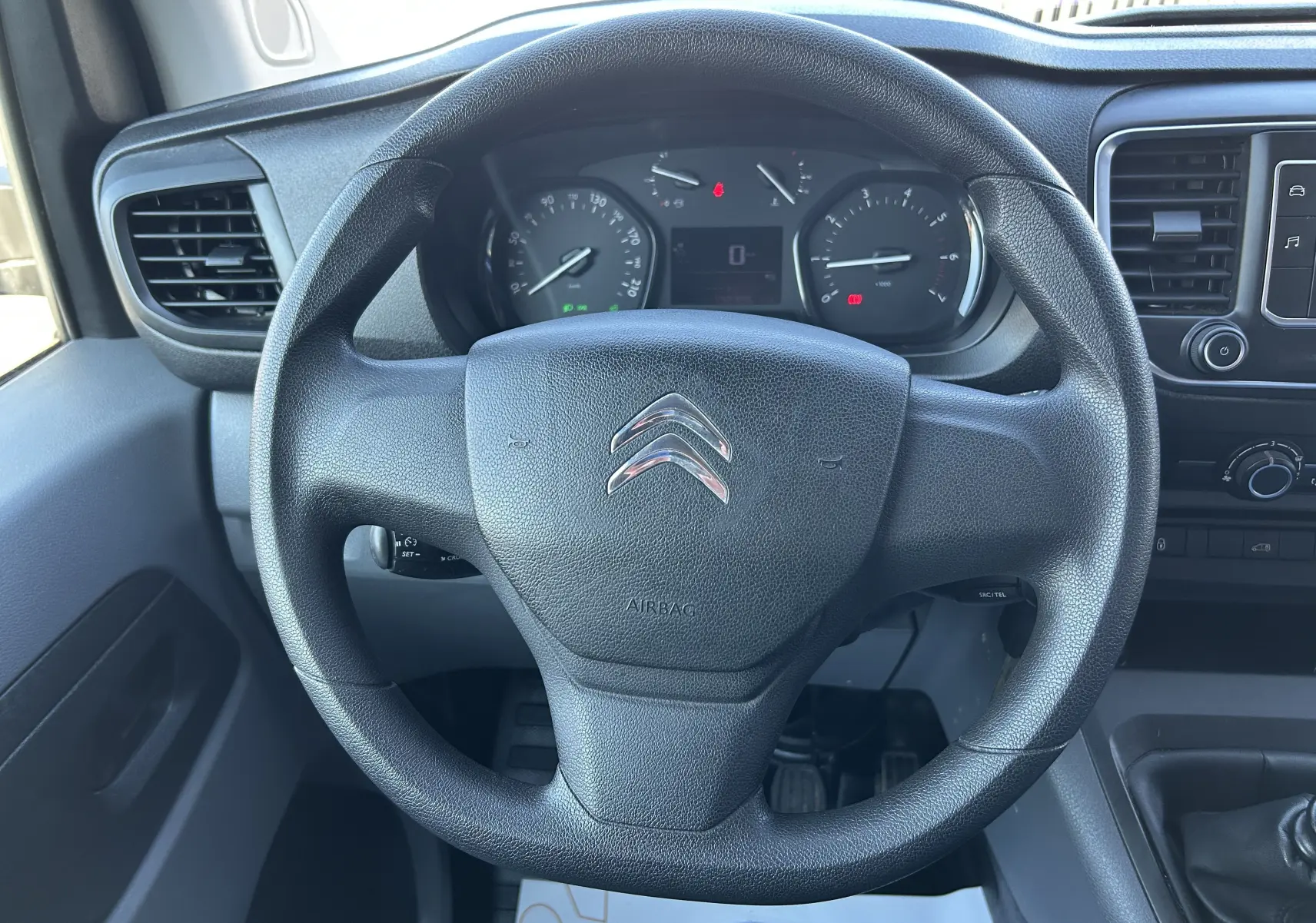 Vue rapprochée du volant noir et du tableau de bord du Citroën Jumpy blanc, avec commandes et compteurs visibles.