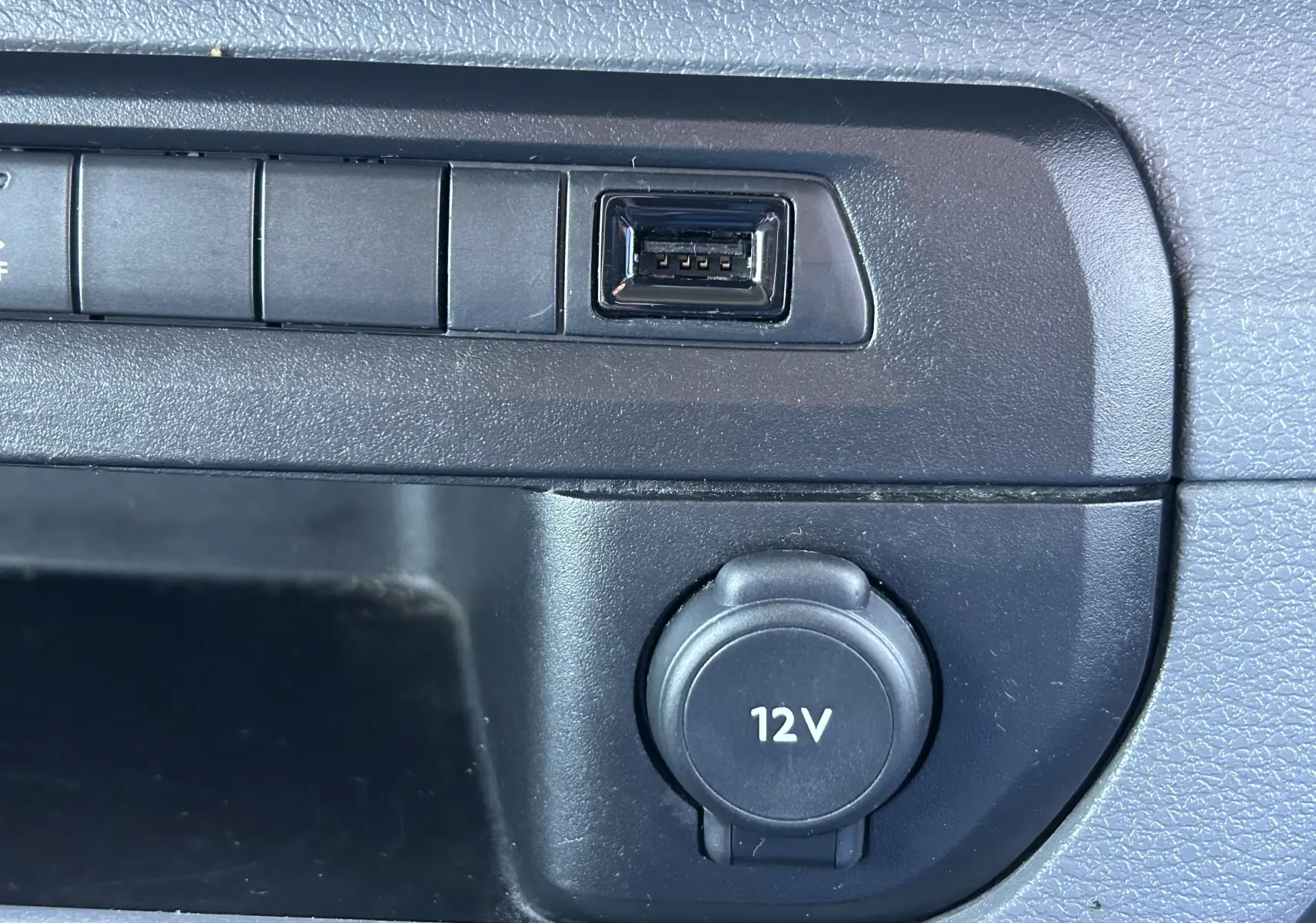 Détail intérieur montrant une prise 12V et un port USB sur le tableau de bord noir du Citroën Jumpy blanc.
