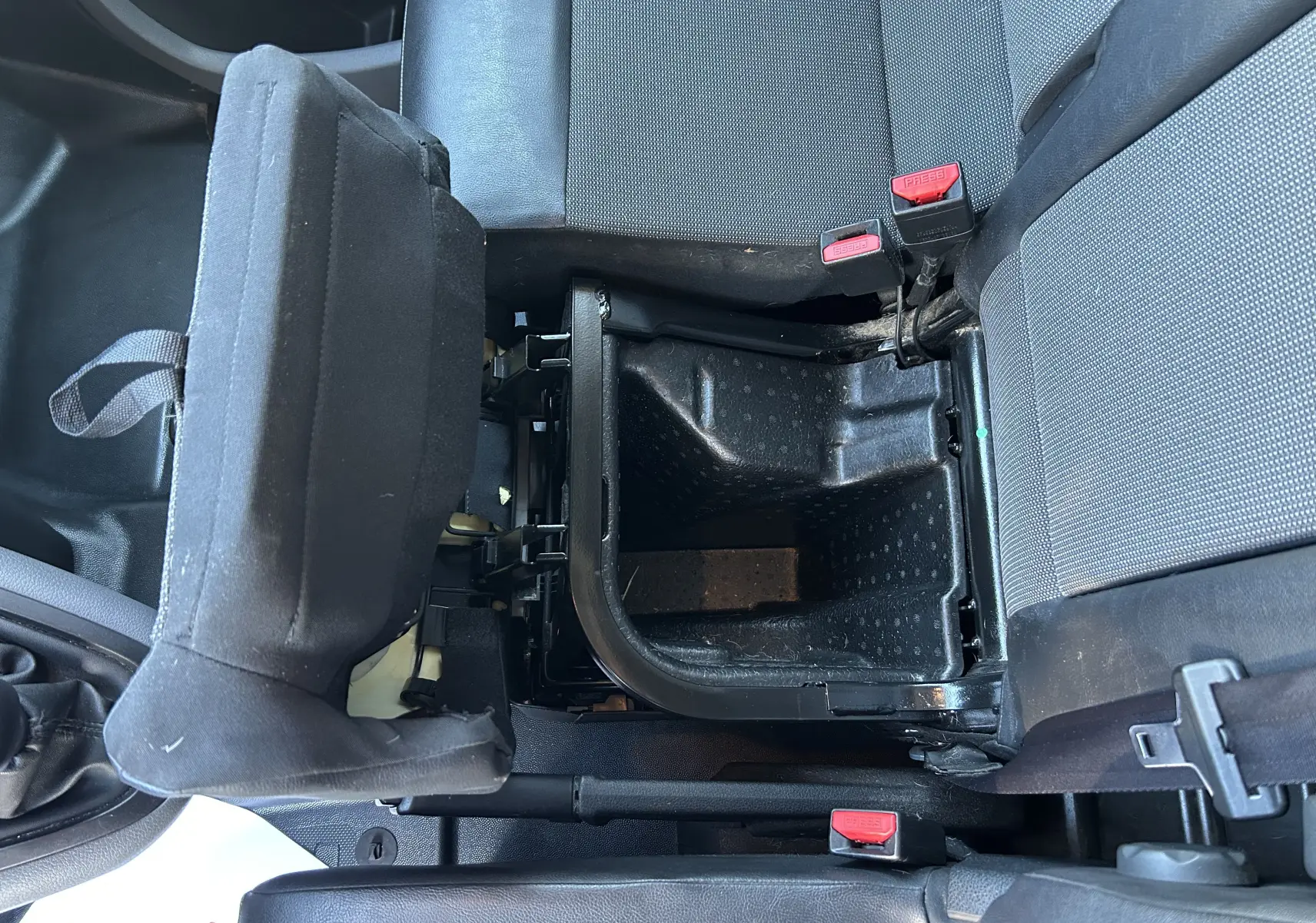 Vue plongeante sur le coffre de rangement ouvert entre les sièges avant gris foncé du Citroën Jumpy blanc.