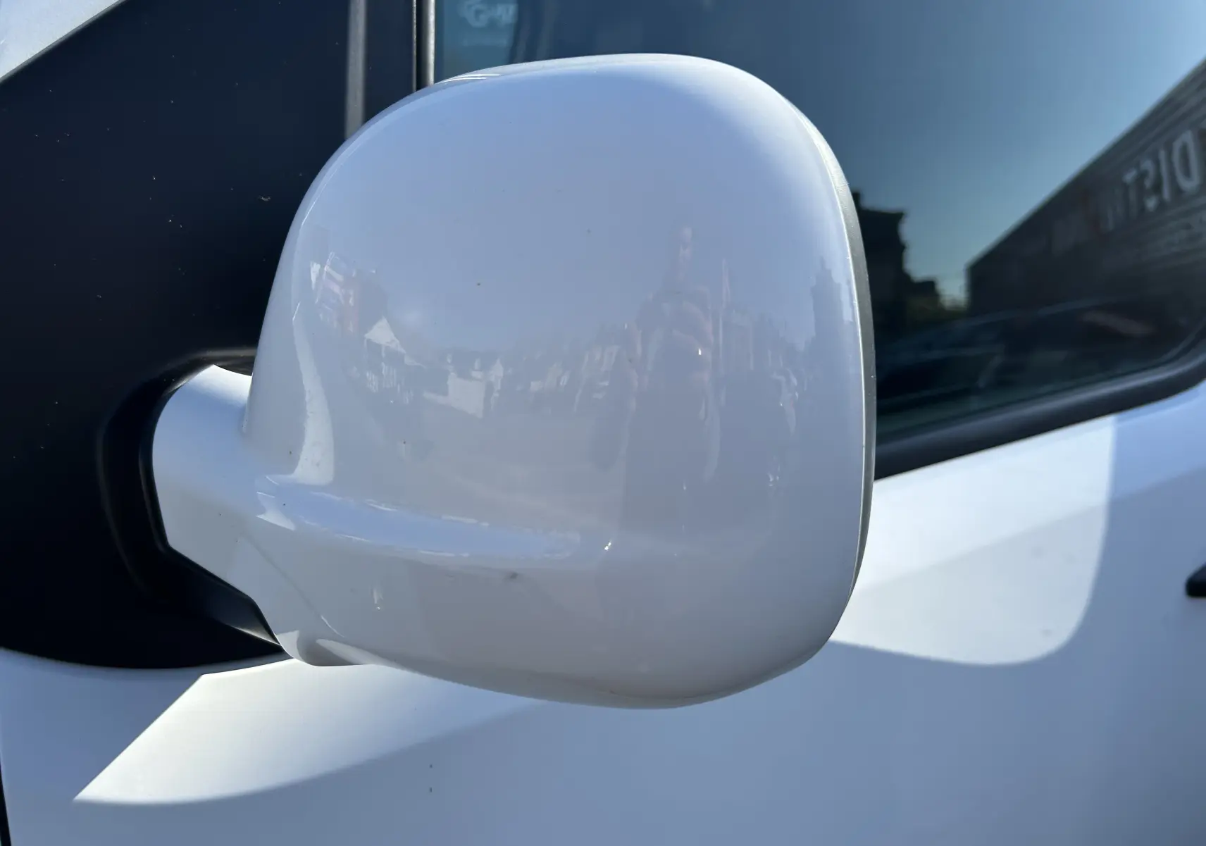 Gros plan sur le rétroviseur droit blanc du Citroën Jumpy fourgon, avec reflet de l'environnement urbain visible.