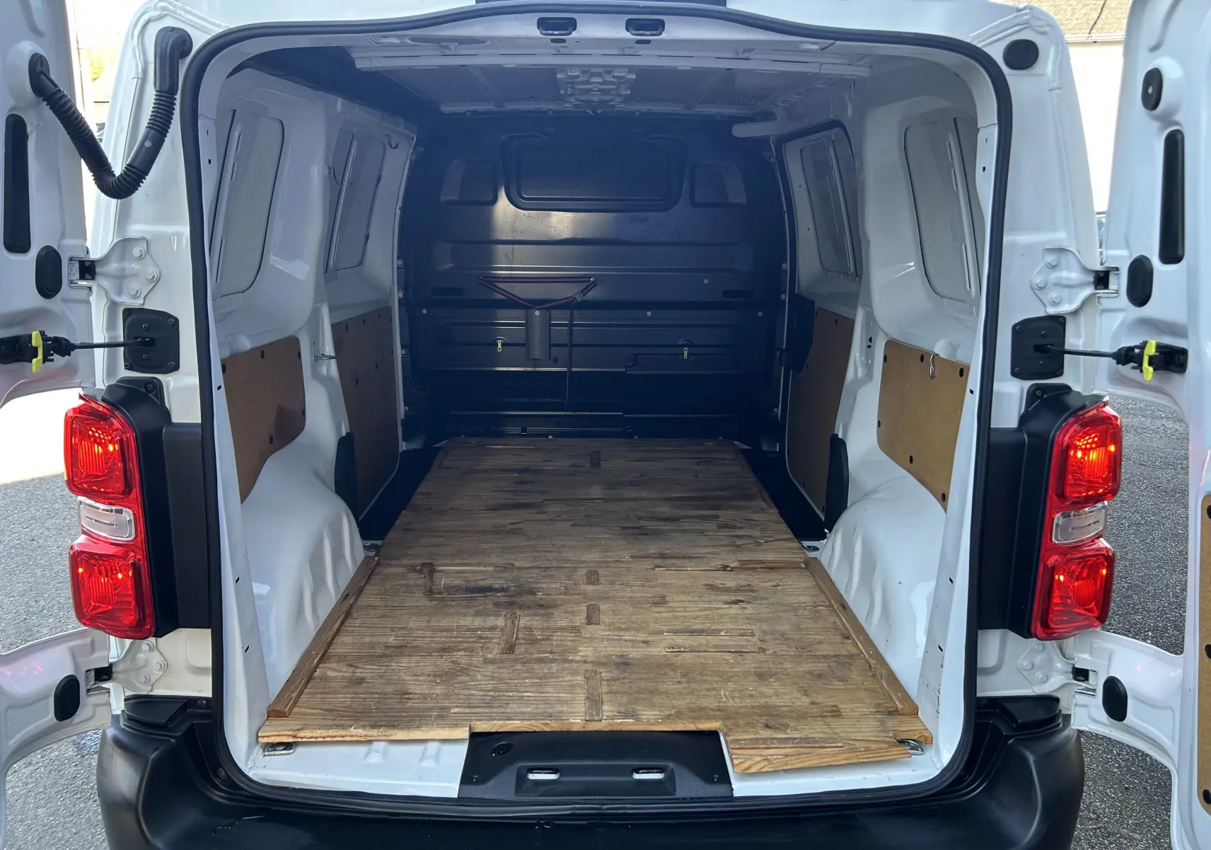Vue arrière ouverte du Citroën Jumpy blanc 2017 montrant l’espace de chargement avec plancher en bois et parois partiellement protégées.
