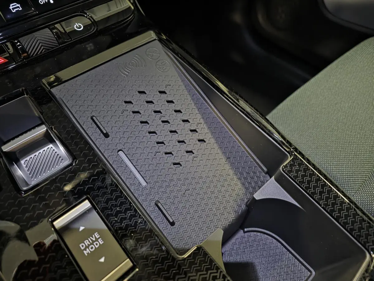 Gros plan sur la console centrale noire brillante du Citroën C5 Aircross 2026 avec zone de recharge sans fil et bouton Drive Mode.