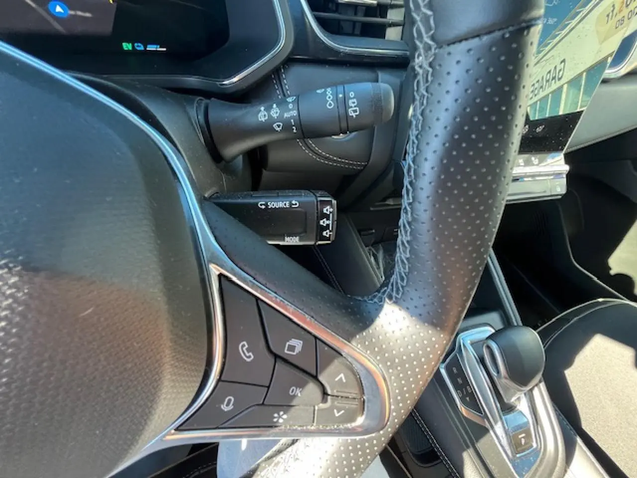 Gros plan sur le volant en cuir perforé et la commande de boîte automatique du Renault Symbioz noir, intérieur moderne et soigné.