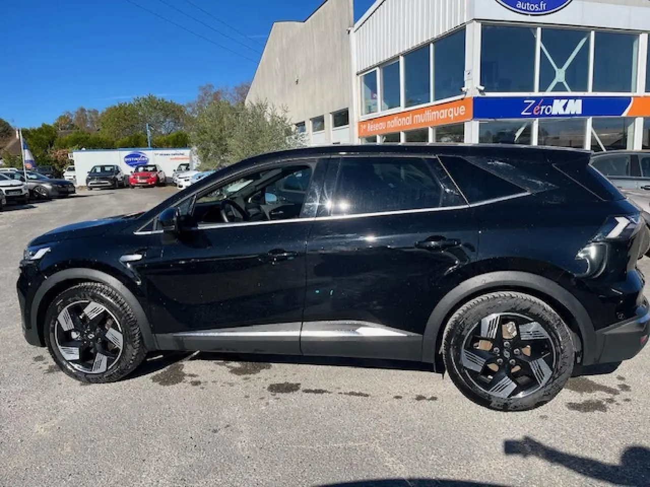 Renault Symbioz 2025 noir étoilé vu de profil côté gauche, avec jantes alliage 19 pouces et vitres surteintées.