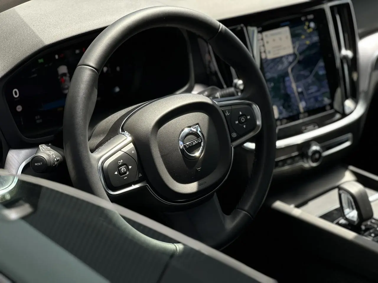 Intérieur du Volvo S60 B4 2024, vue rapprochée du volant avec commandes intégrées et écran tactile multimédia.