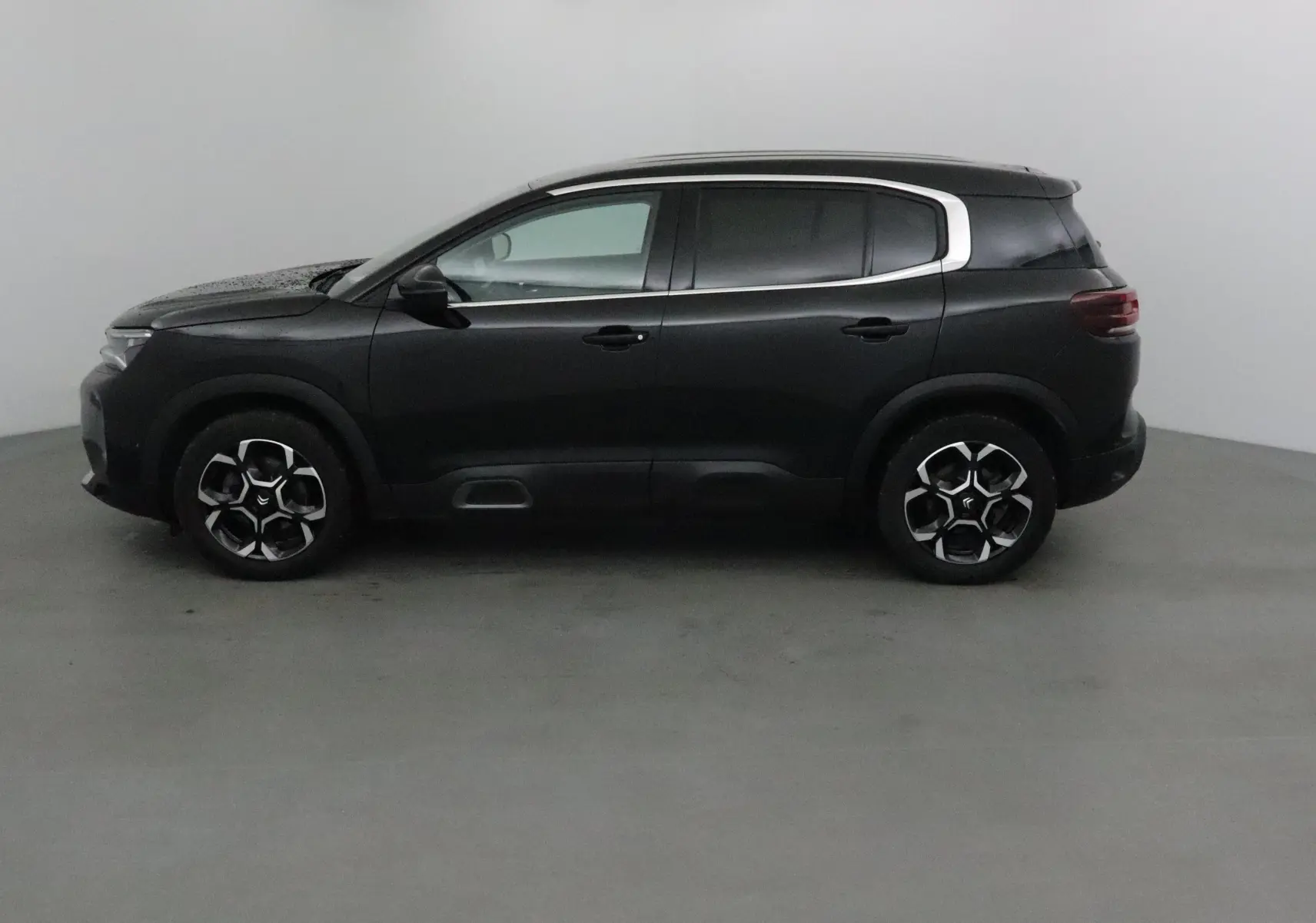 Profil côté gauche d'un Citroën C5 Aircross noir 2024 avec jantes noires et détails chromés autour des vitres.