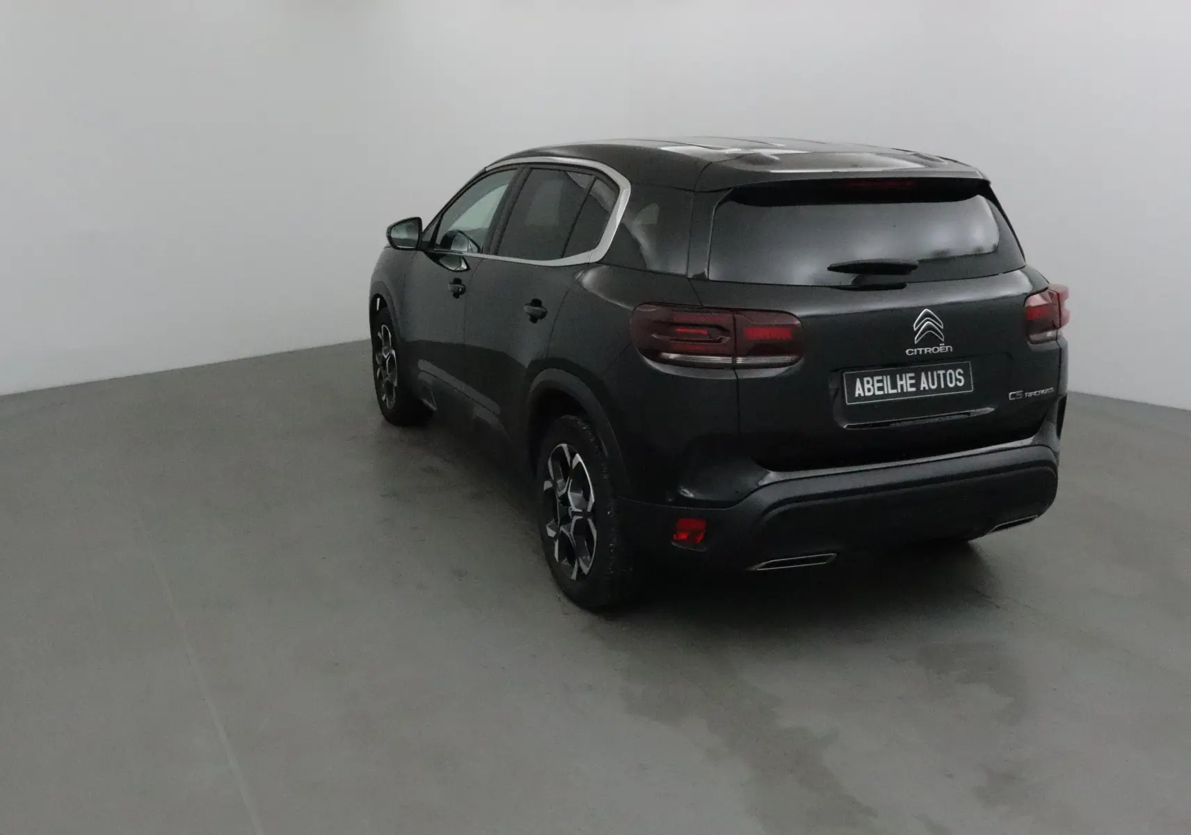 Vue 3/4 arrière d'un SUV Citroën C5 Aircross noir avec jantes alliage et vitres teintées en intérieur neutre.