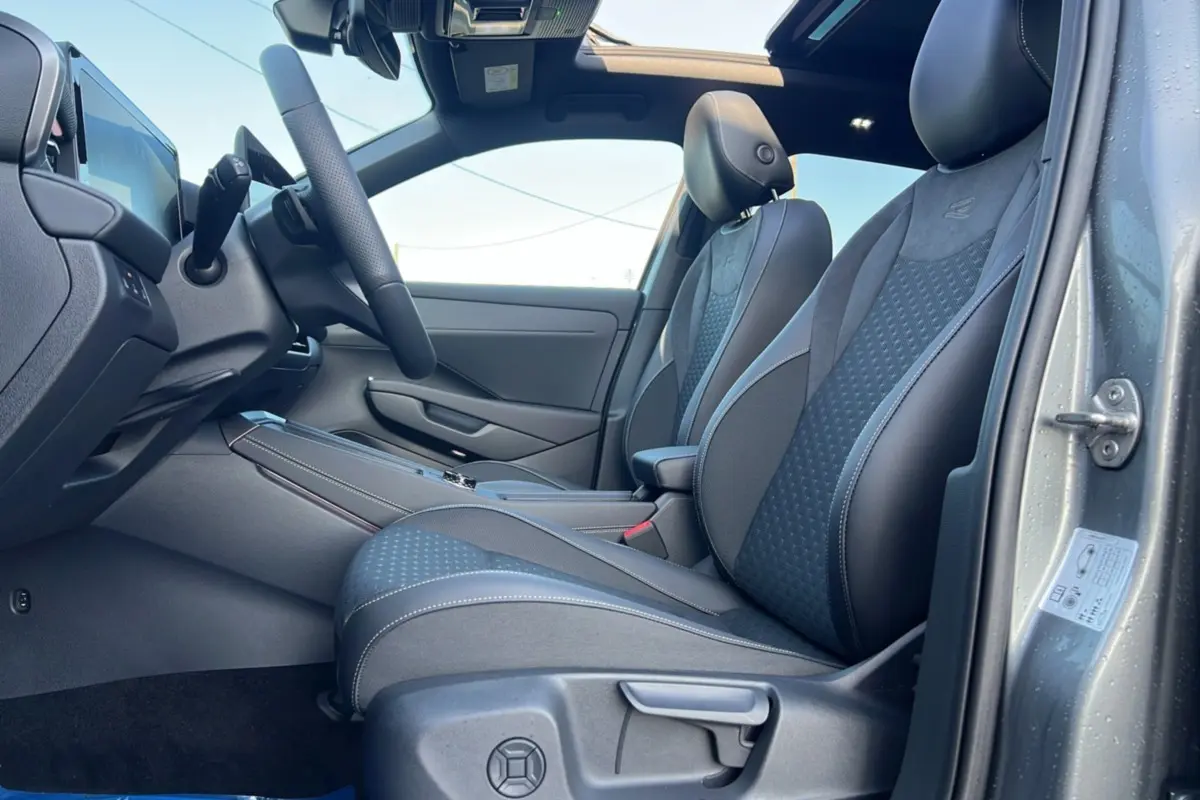 Vue intérieure côté conducteur du Volkswagen T-Roc gris loup, sièges R-Line en tissu et alcantara avec surpiqûres blanches.