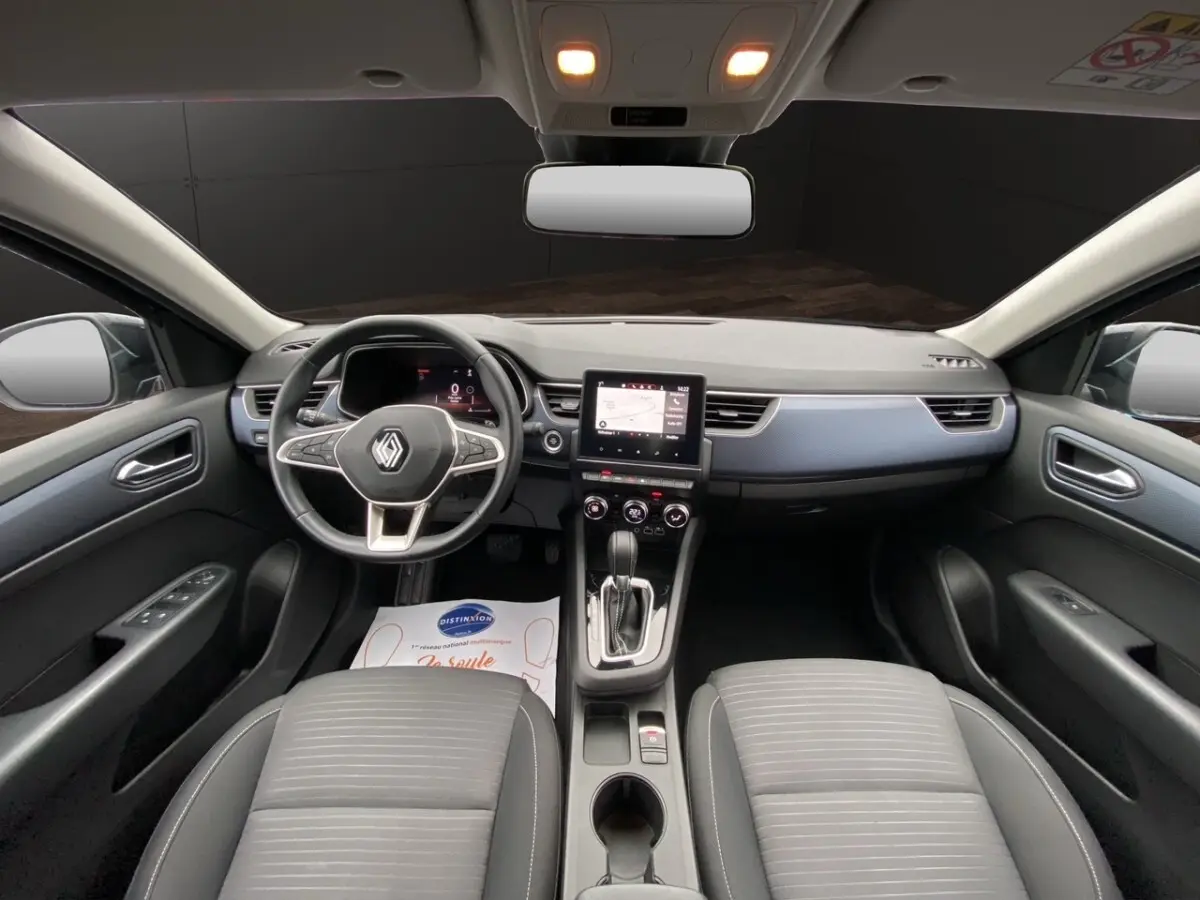 Vue intérieure avant du Renault Arkana 2024 noir, montrant le tableau de bord avec écran tactile central et volant multifonctions.